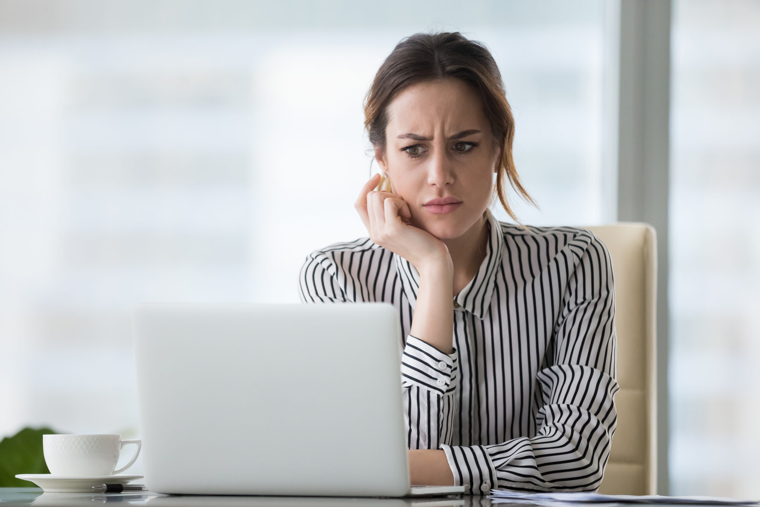 Confused businesswoman annoyed by online problem looking at laptop