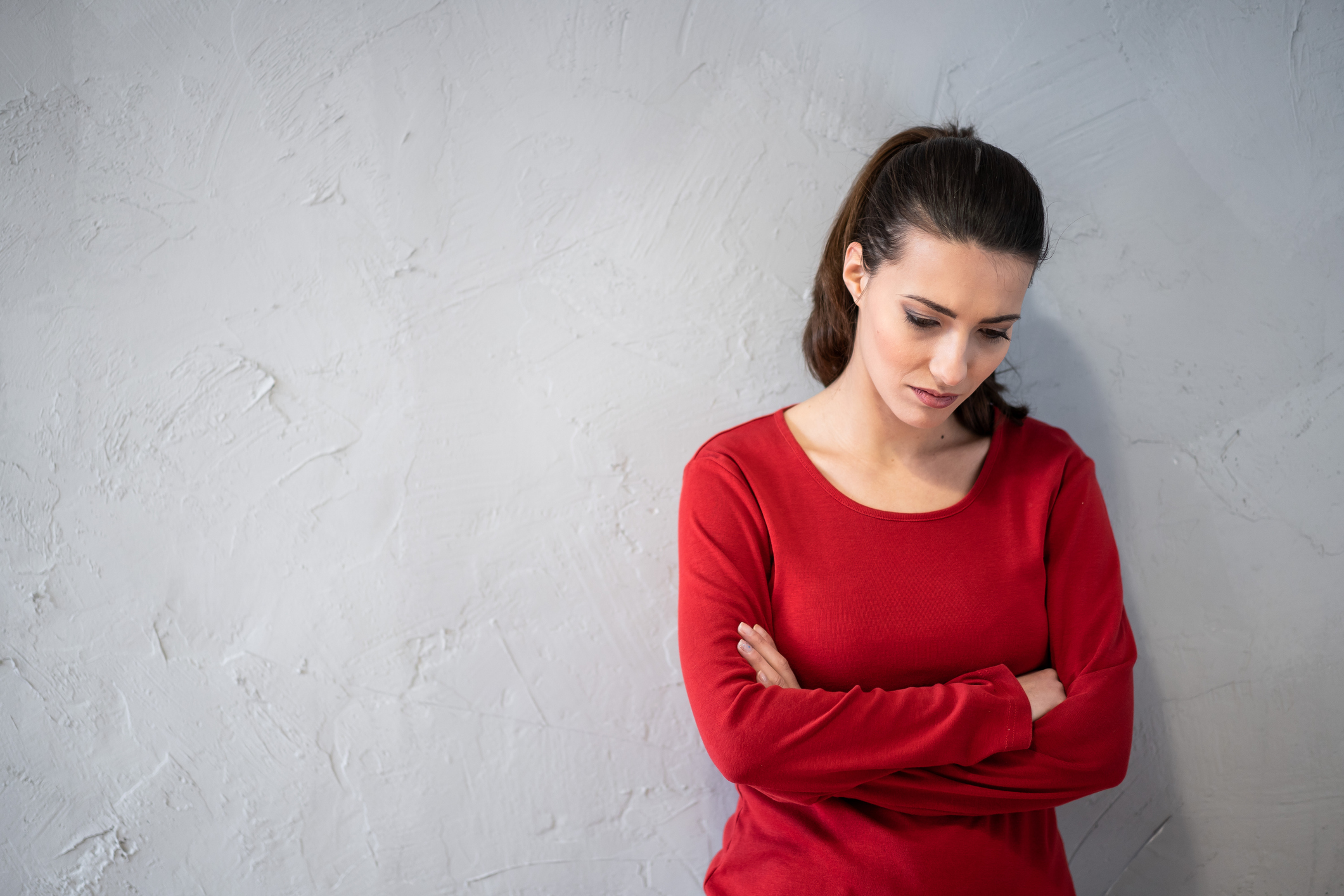 Unhappy woman woman standing with arms crossed on gray background