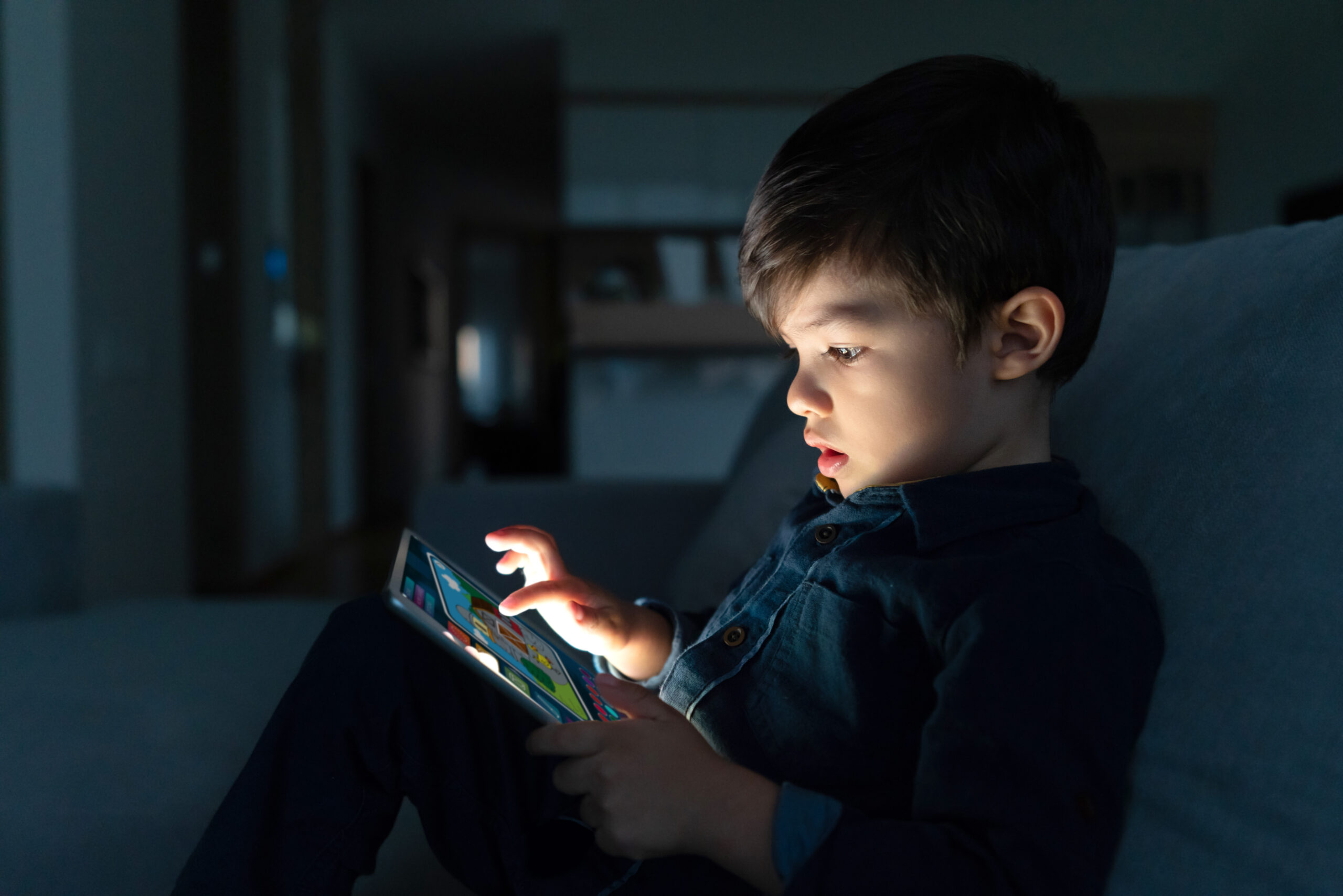 Young boy using a digital tablet at home at nighttime