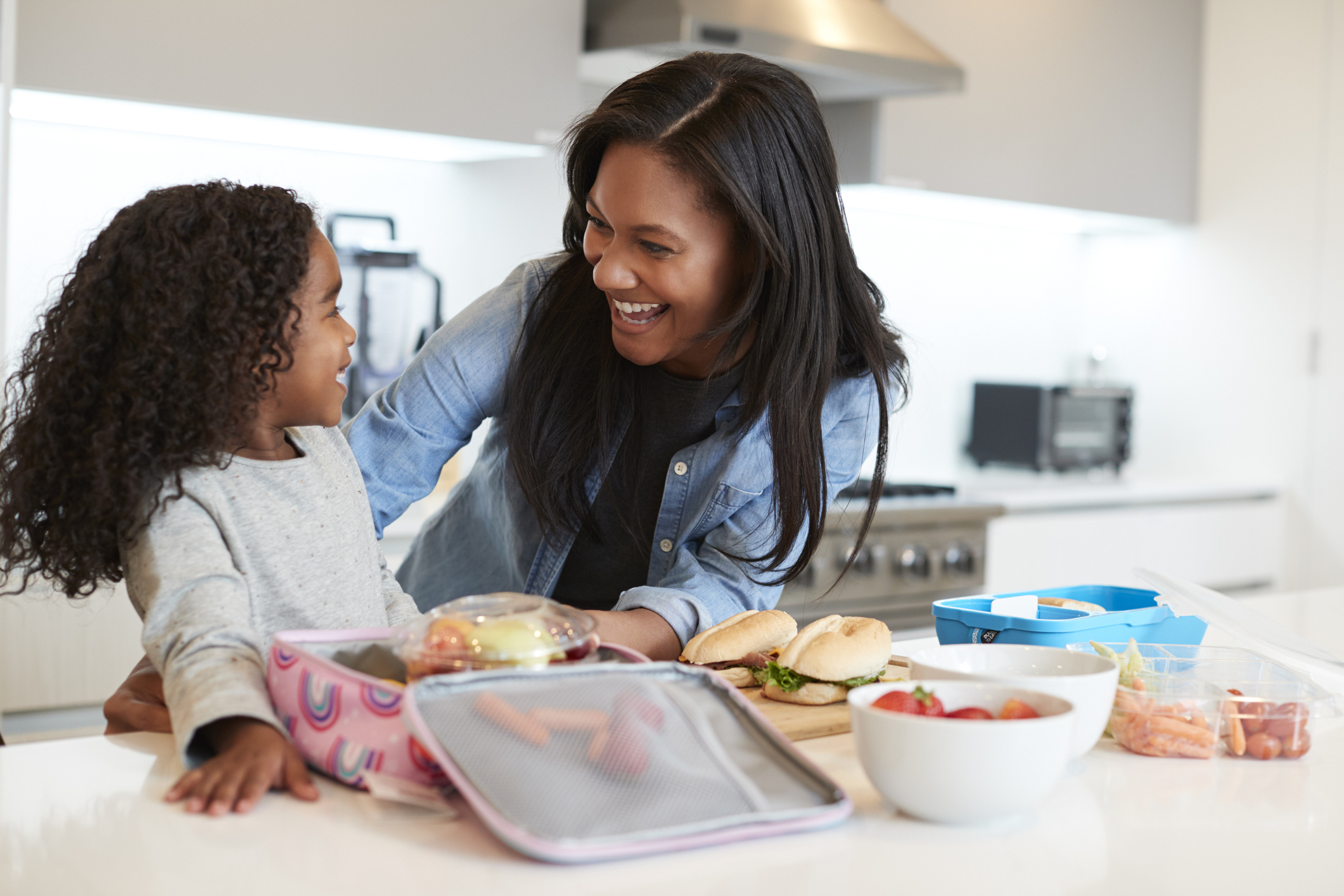 Daughter In Kitchen At Home Helping Mother To Make Healthy Packed Lunch