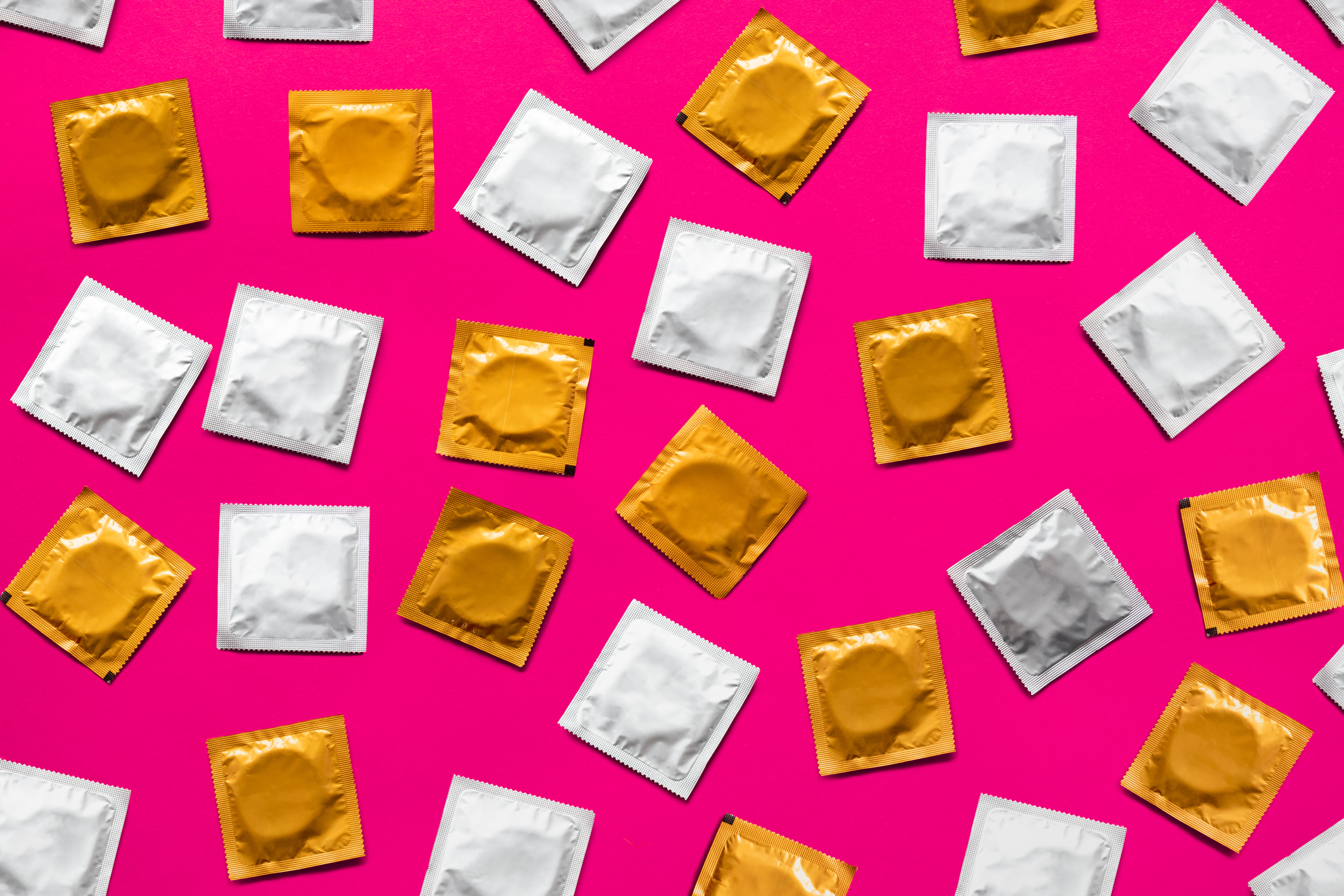 Condoms in pink background, top view.