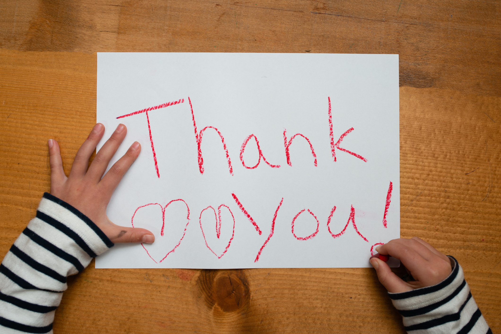 Child writes thank you on paper