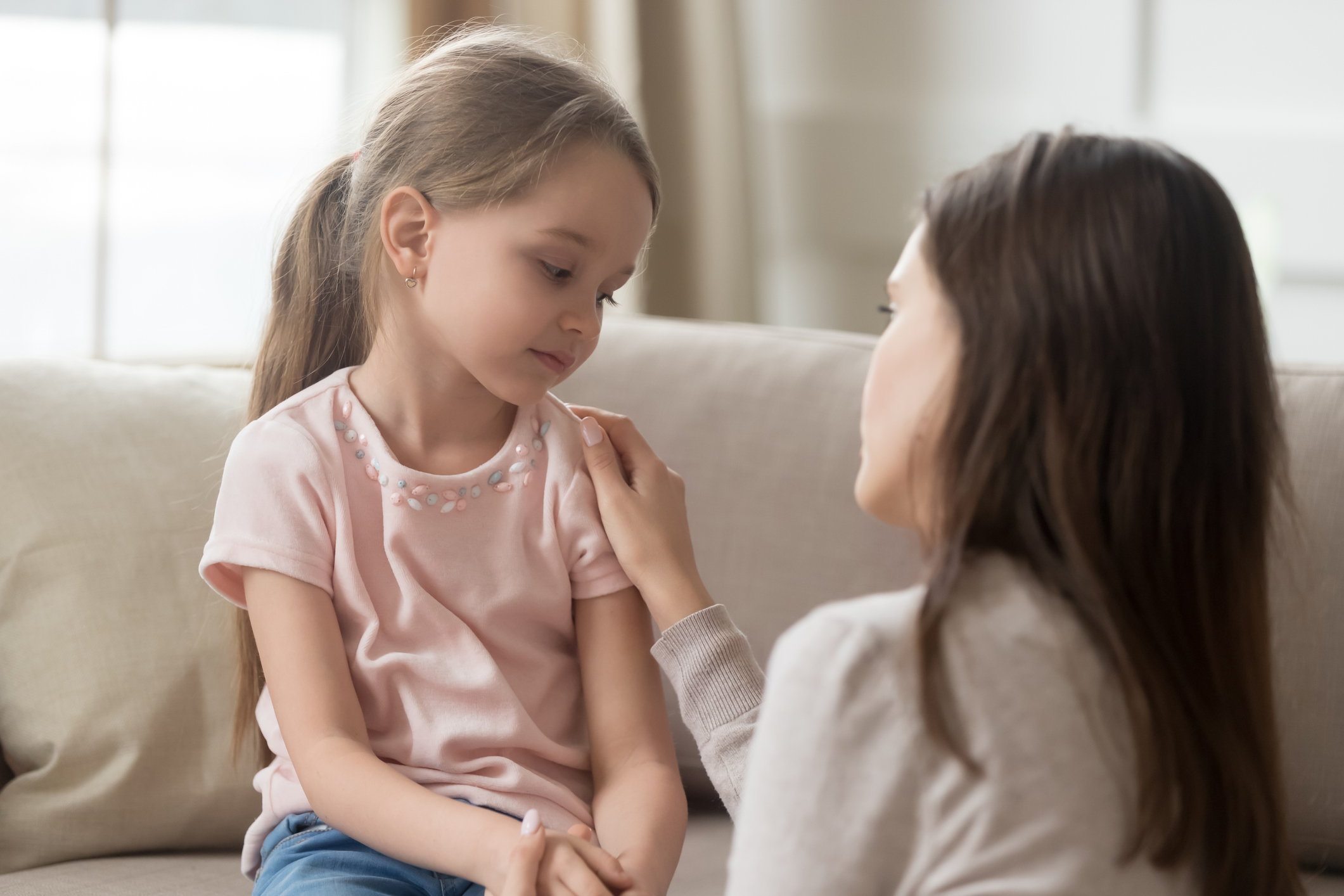 Loving mom talking to upset little child girl giving support