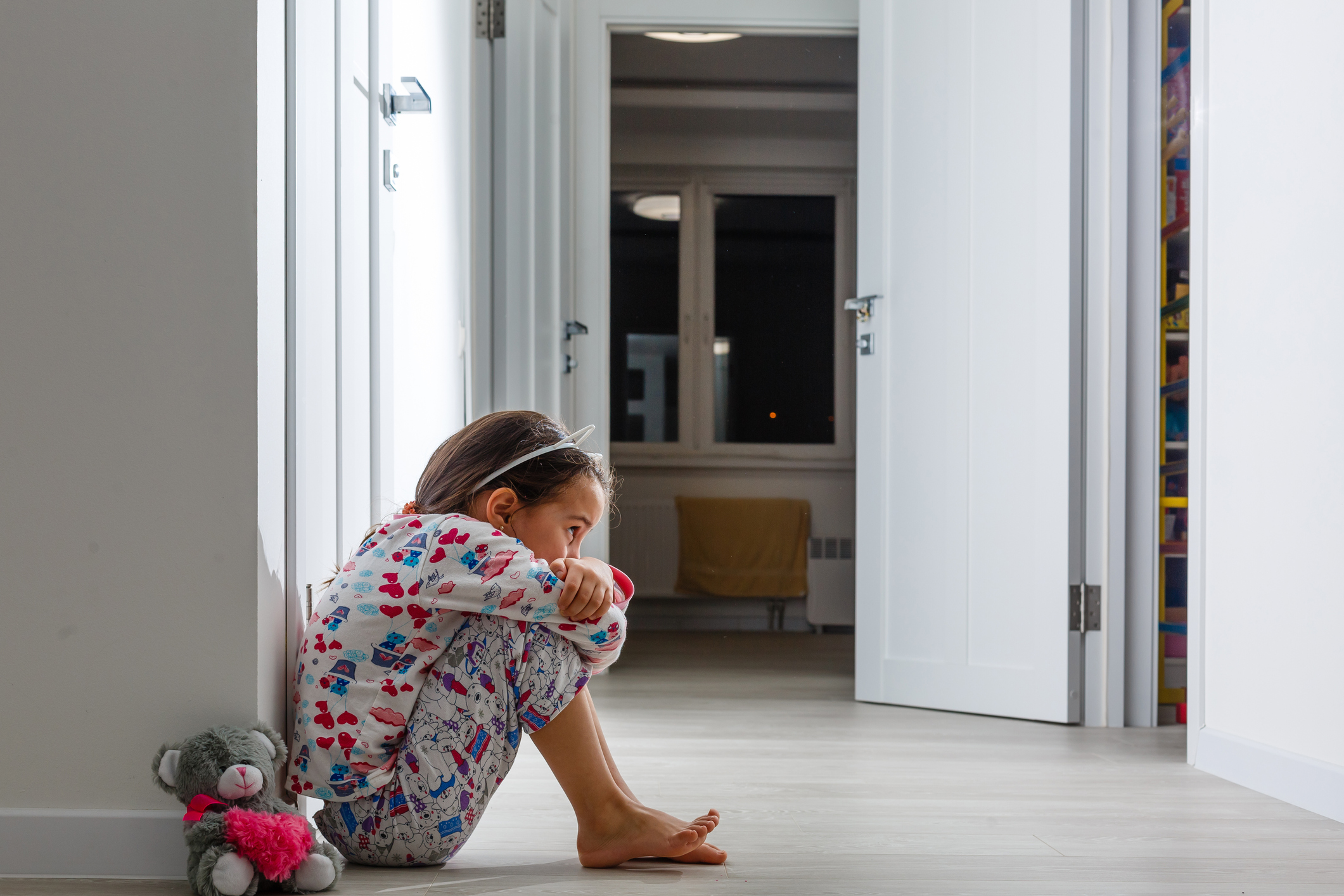 Sad little girl sitting near the wall