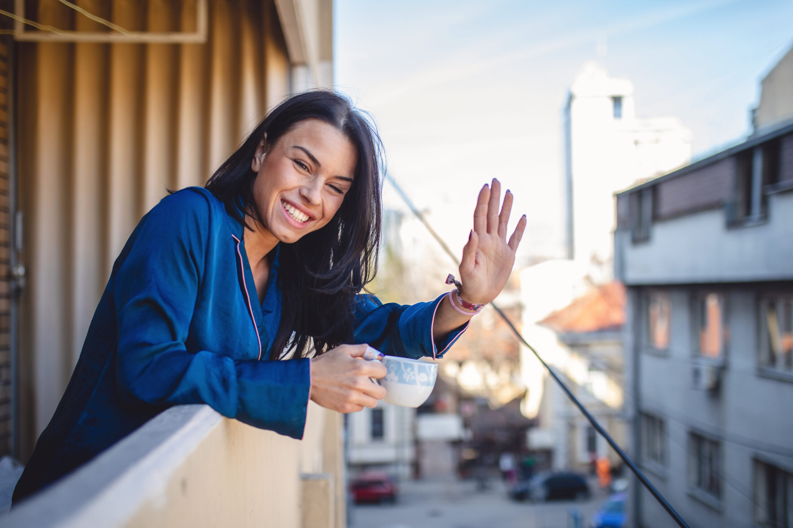 Smiling neighbor waving while enjoying a cup of coffee