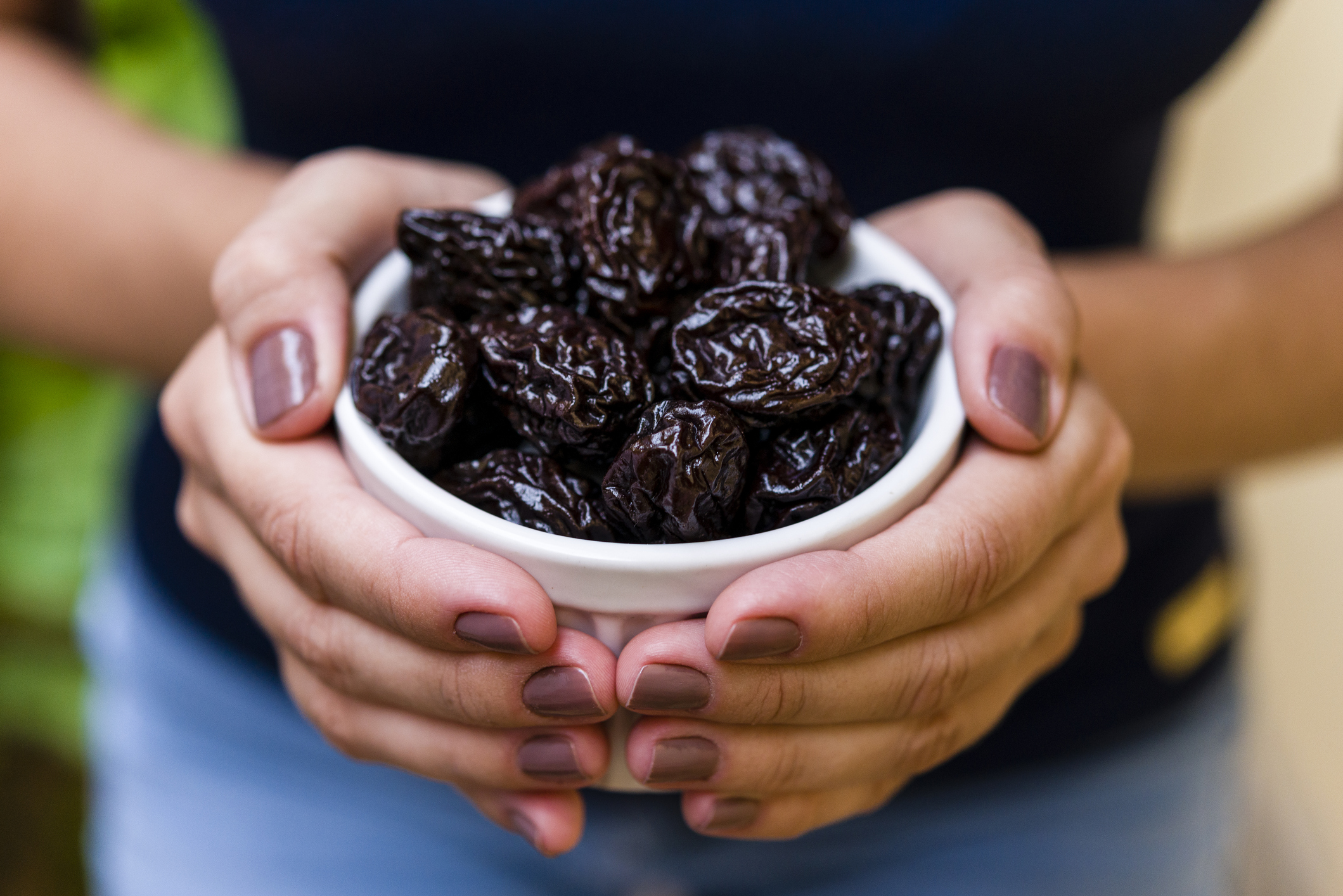 Hand of brunette model holding white pot with dried plum