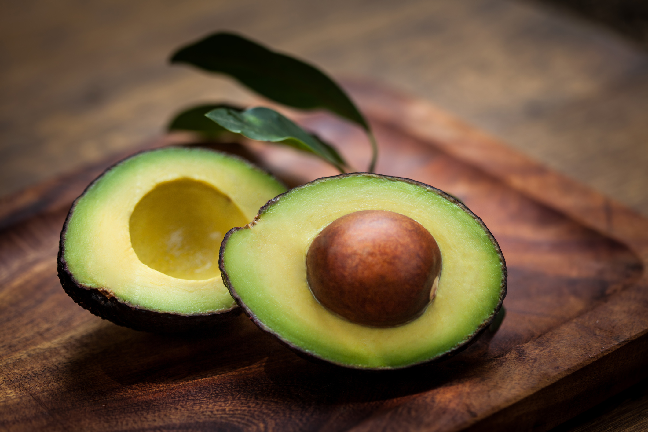 Avocado halves on a wooden board