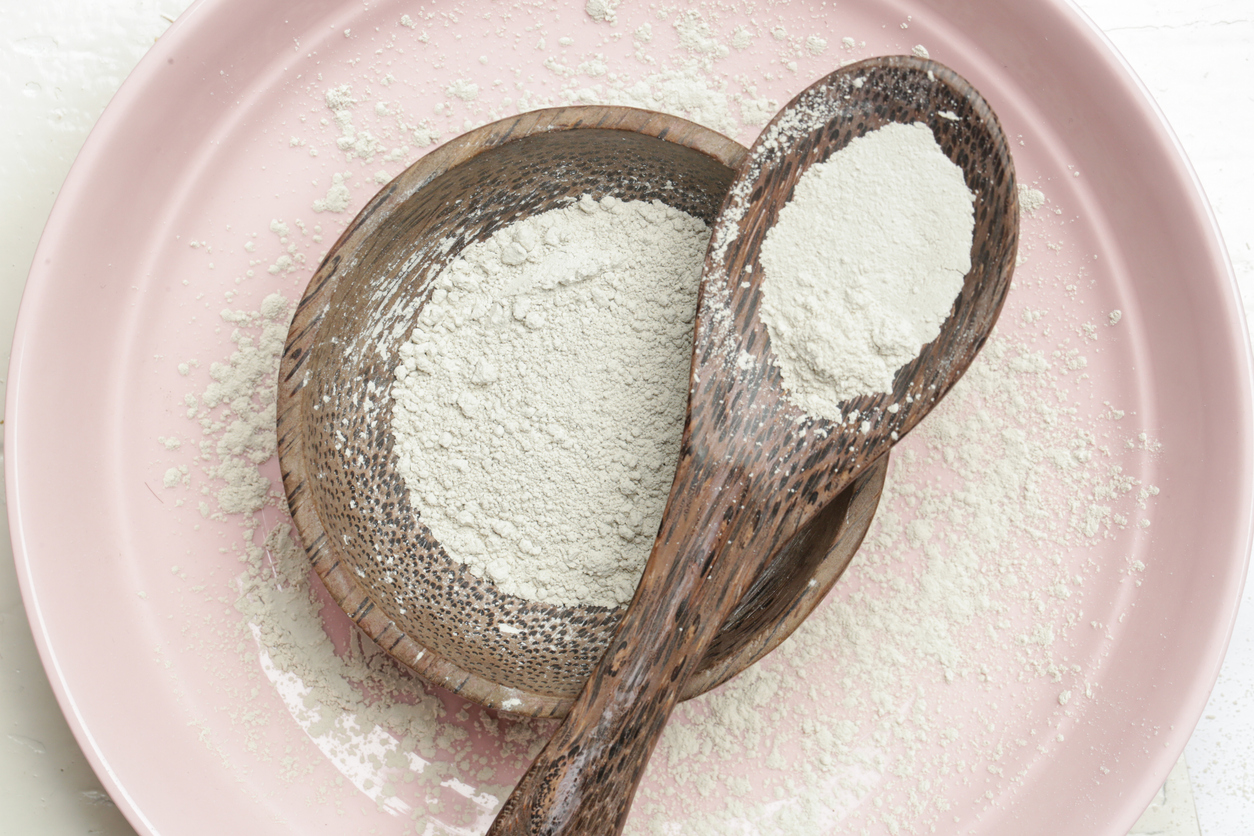 Top view of cosmetic clay powder in a wooden bowl