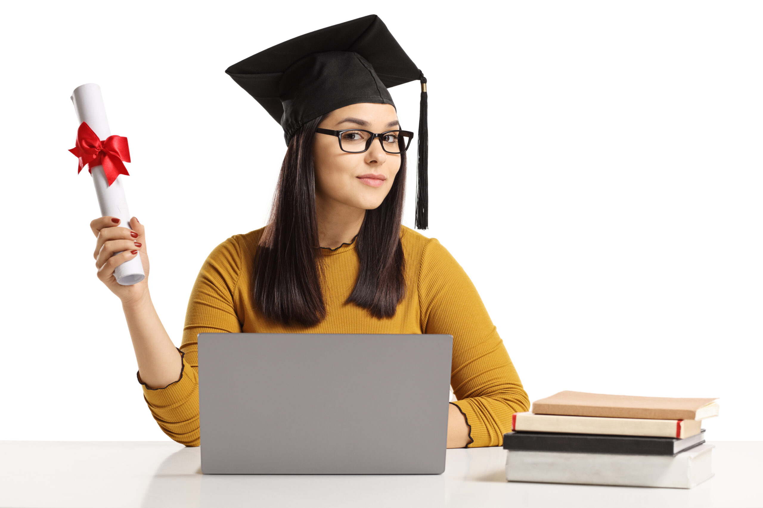 Young woman with a graduation hat and diploma sitting with a laptop and books