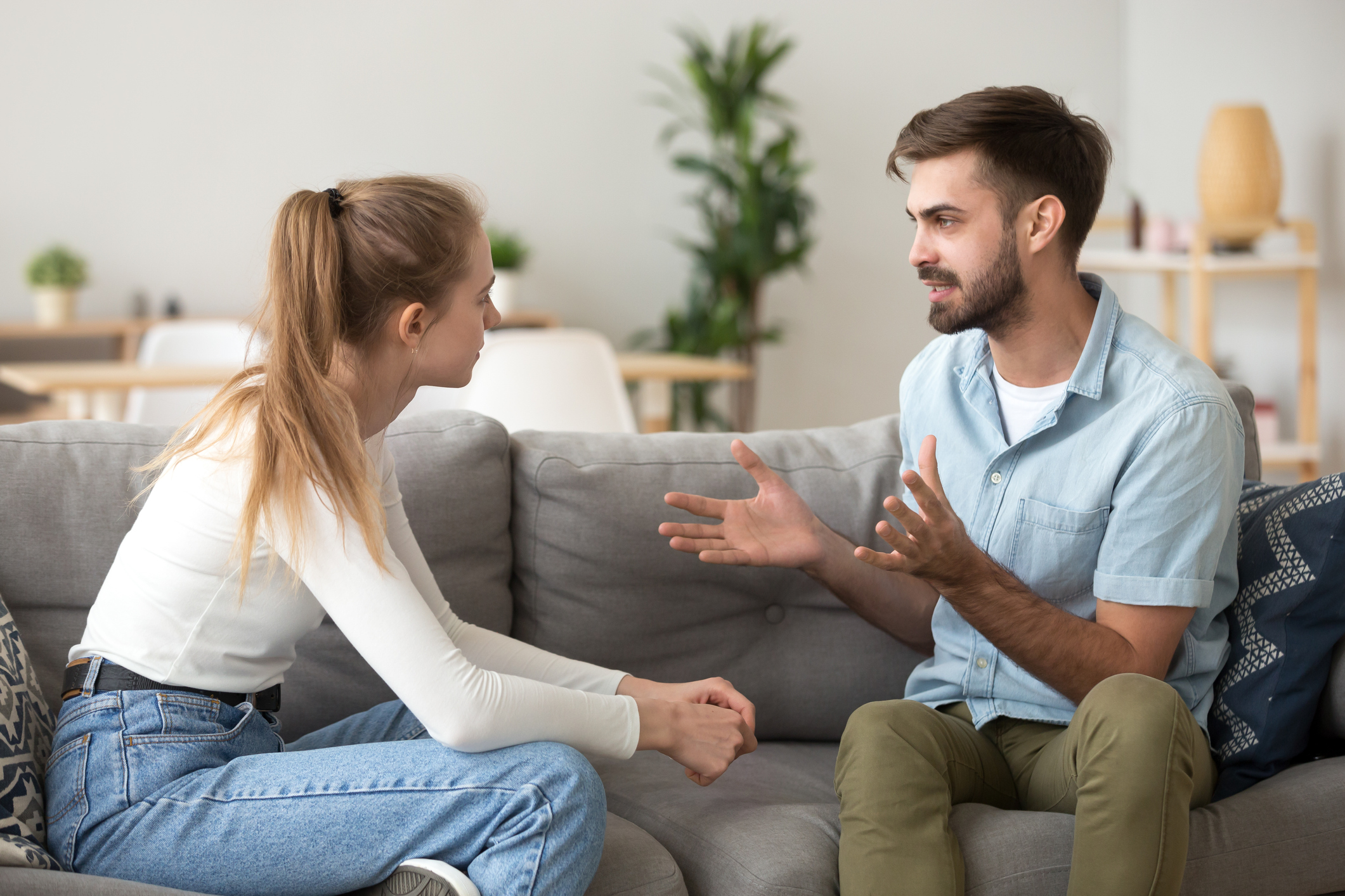 Serious young couple sitting together, talking about relationships