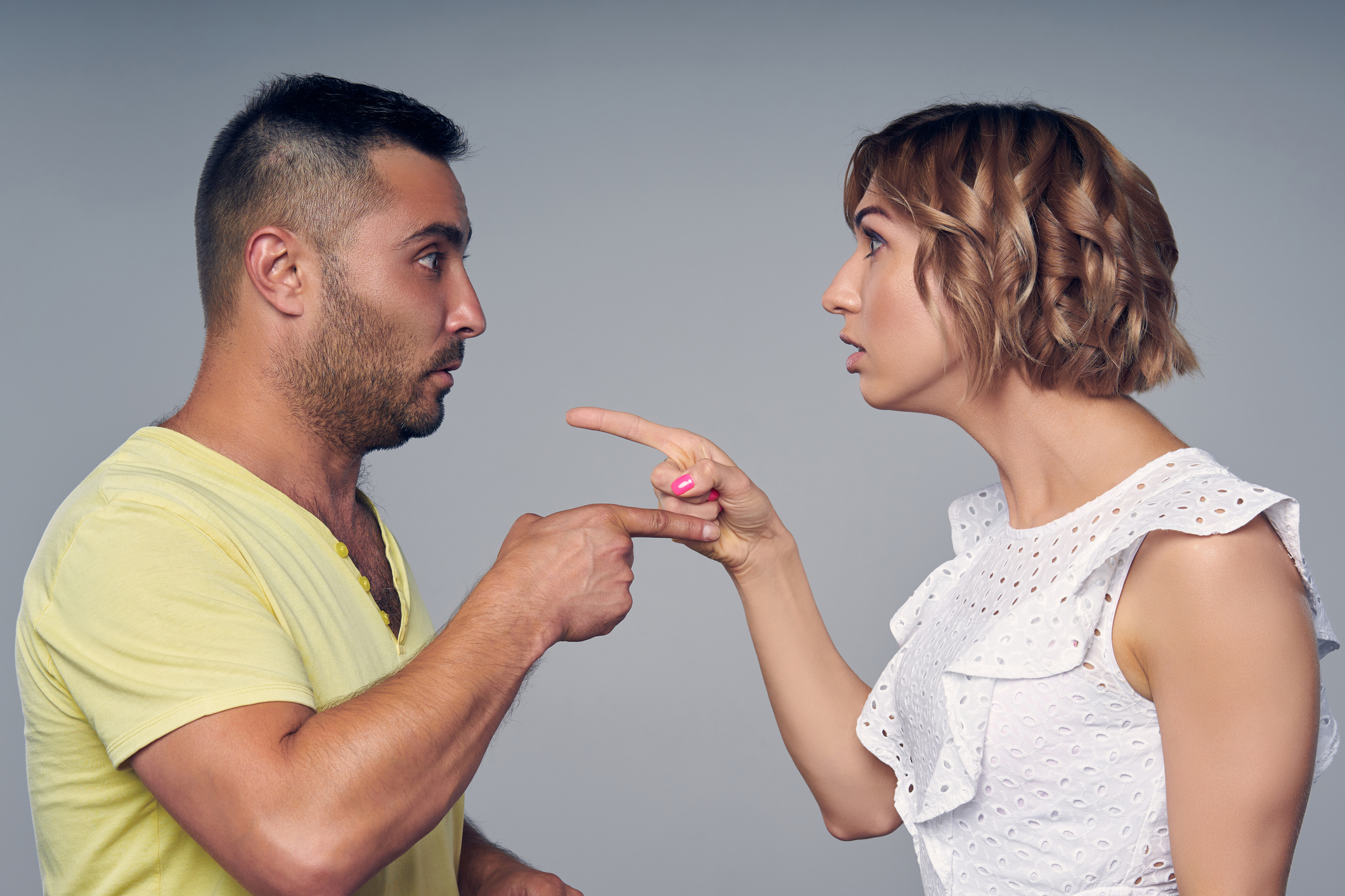 A couple man and woman pointing at each other expressing accusation