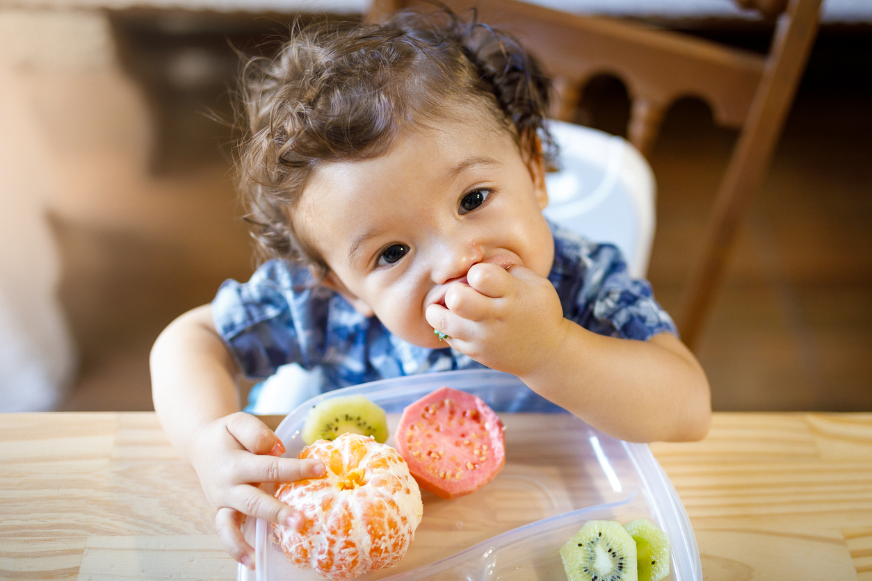 Baby boy eating tasty fruit