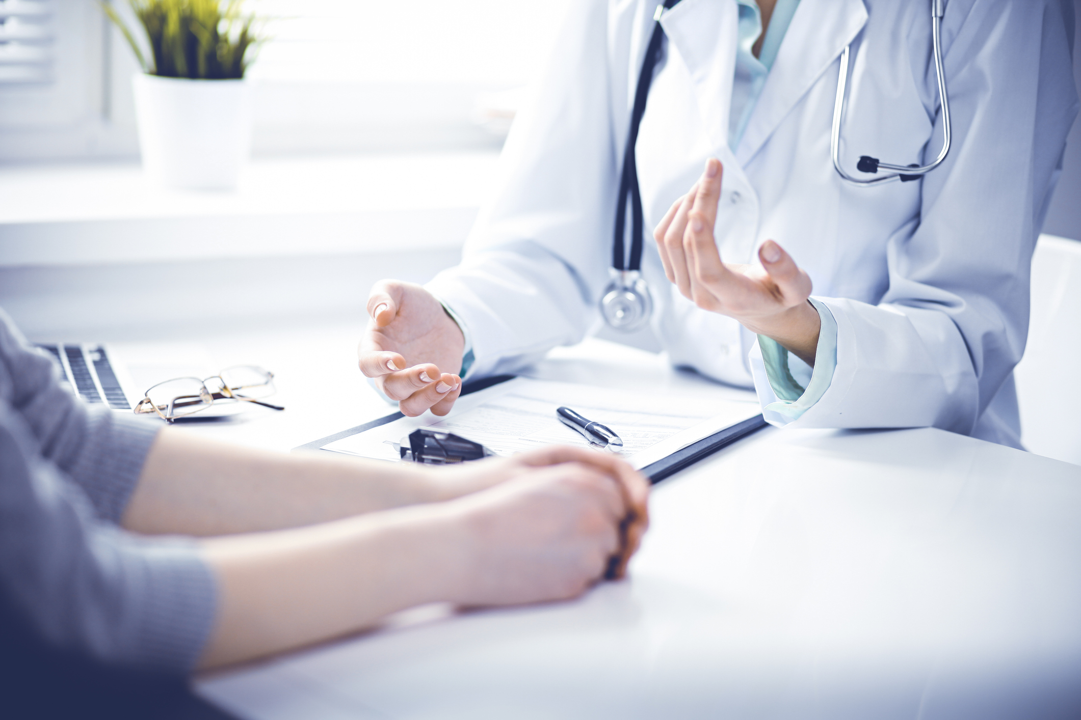 Doctor and  female patient sitting at the desk and talking  in clinic near window. Medicine and health care concept. Green is main color