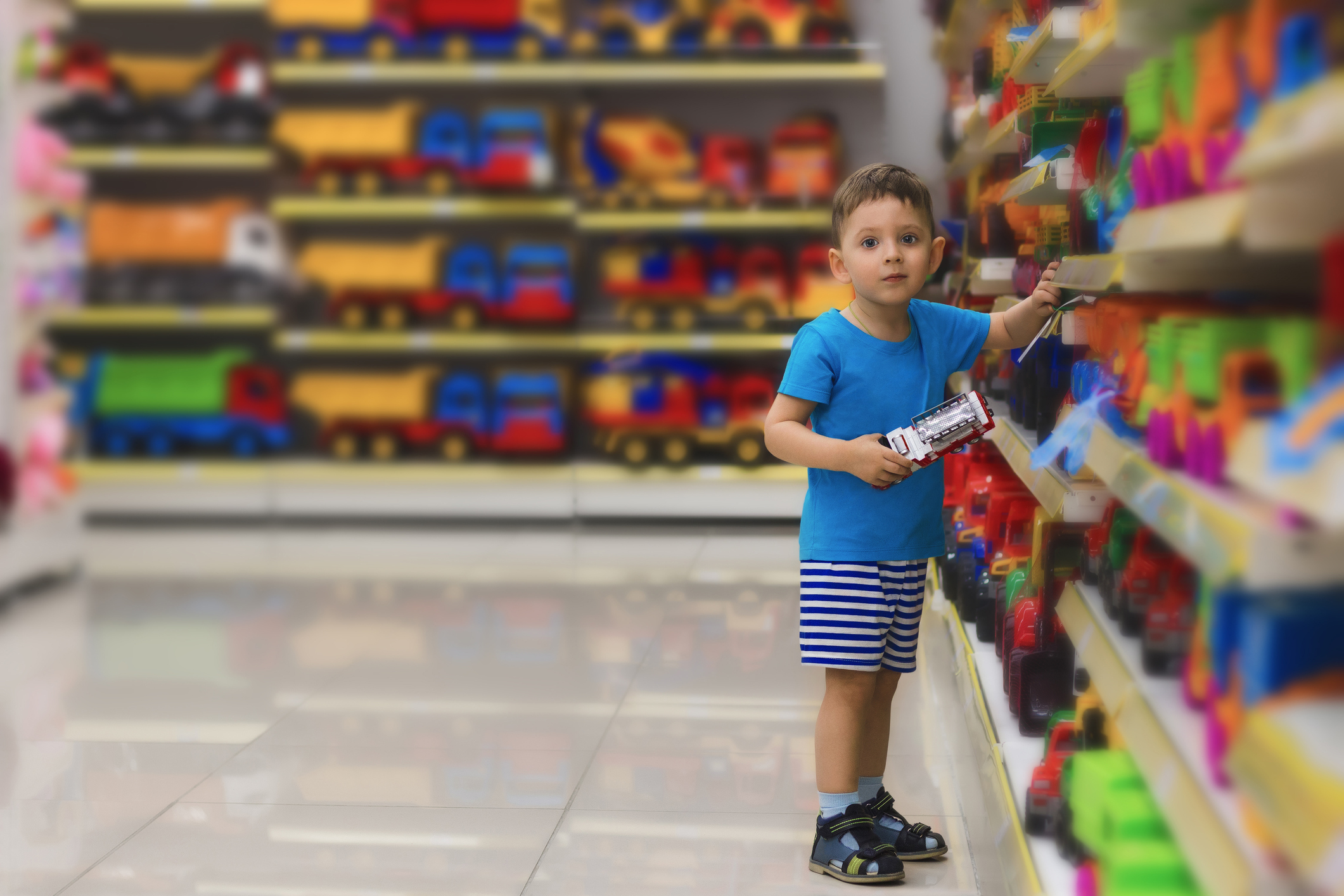 Little child loking at showcase and choosing toys at the kids store. Shopping for children. Baby shop.