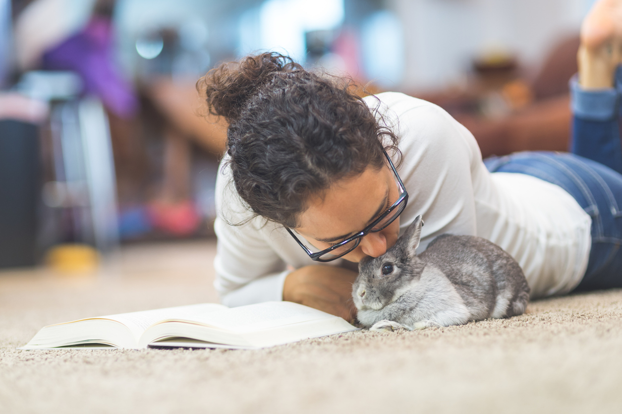 Young woman reads and snuggles with her pet bunny