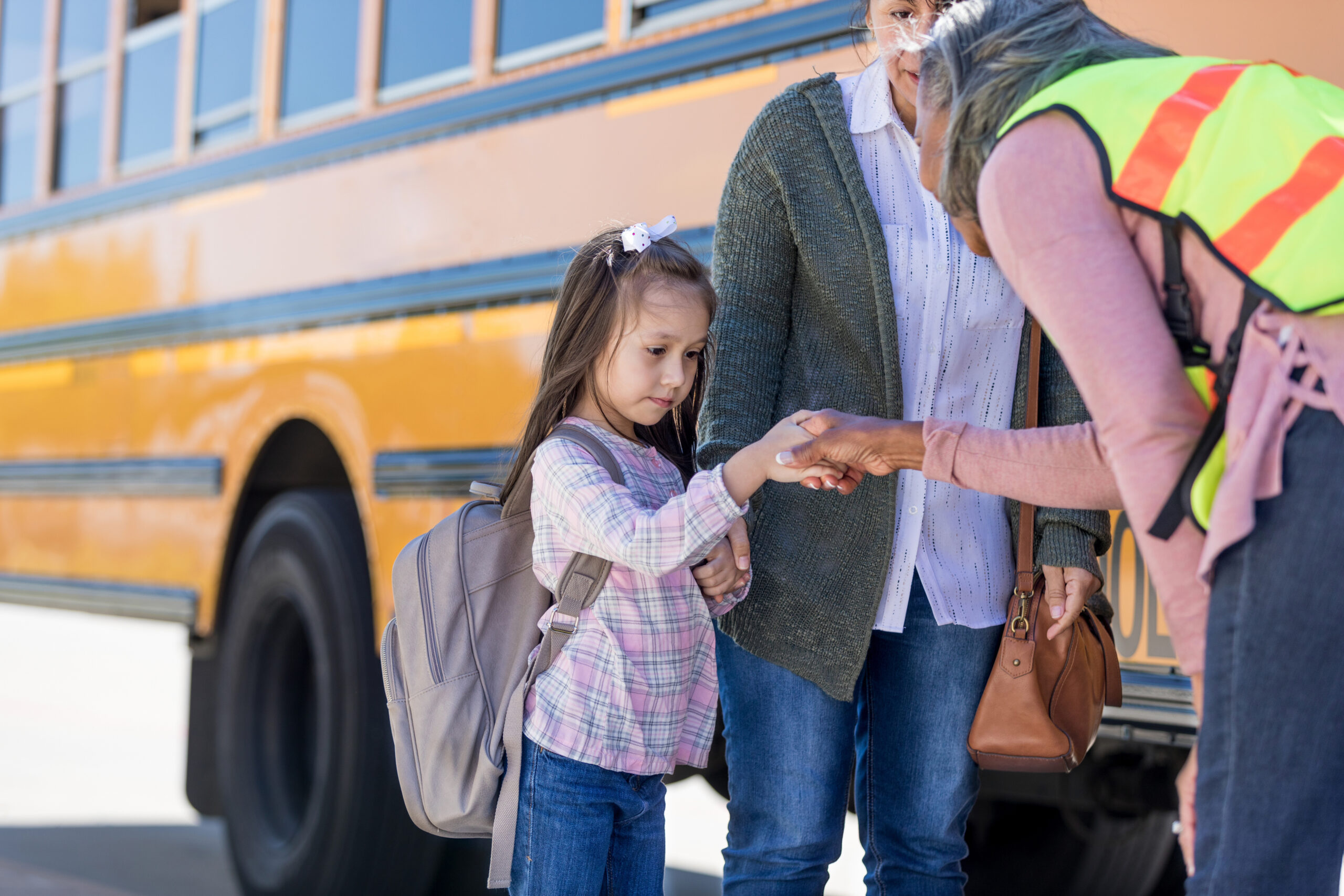 A school bus driver shakes hands with shy schoolgirl