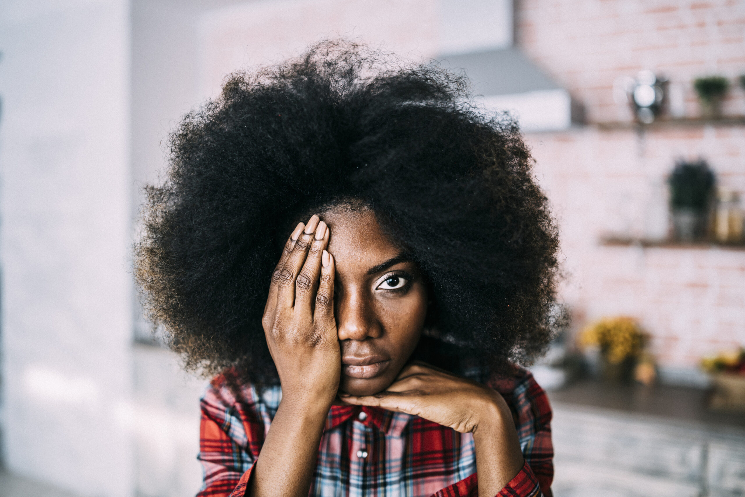 African woman sitting at home, hiding face