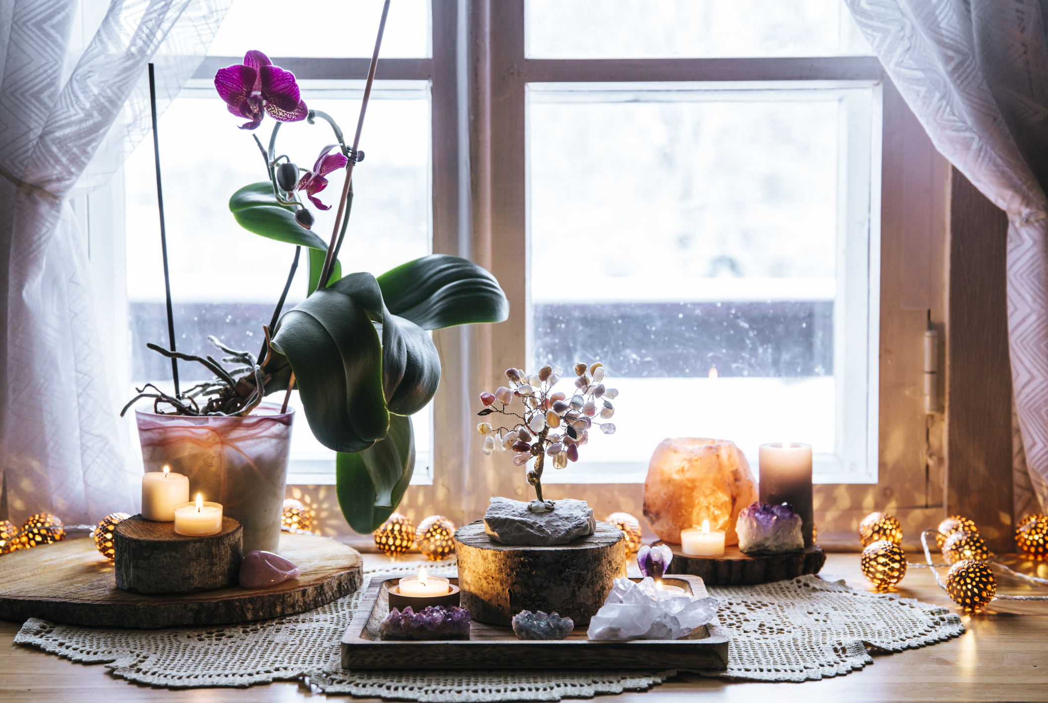 Feng Shui nature theme altar at home table and on window sill. Earth element( rock crystal clusters), wood element( wood discs), fire element( candles), rock salt candle holder. Positive home energy.