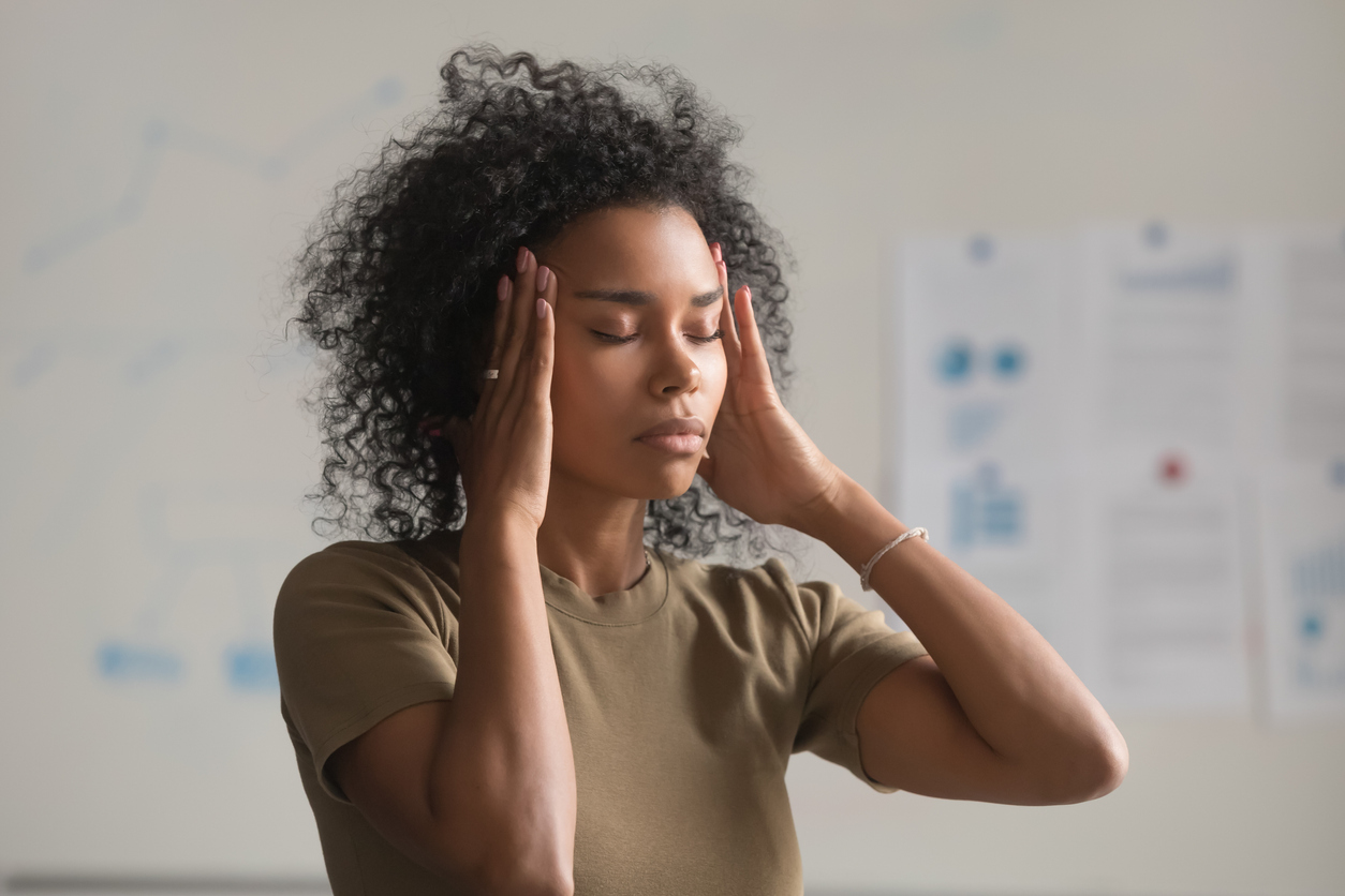 Exhausted black woman worker massage temples having headache