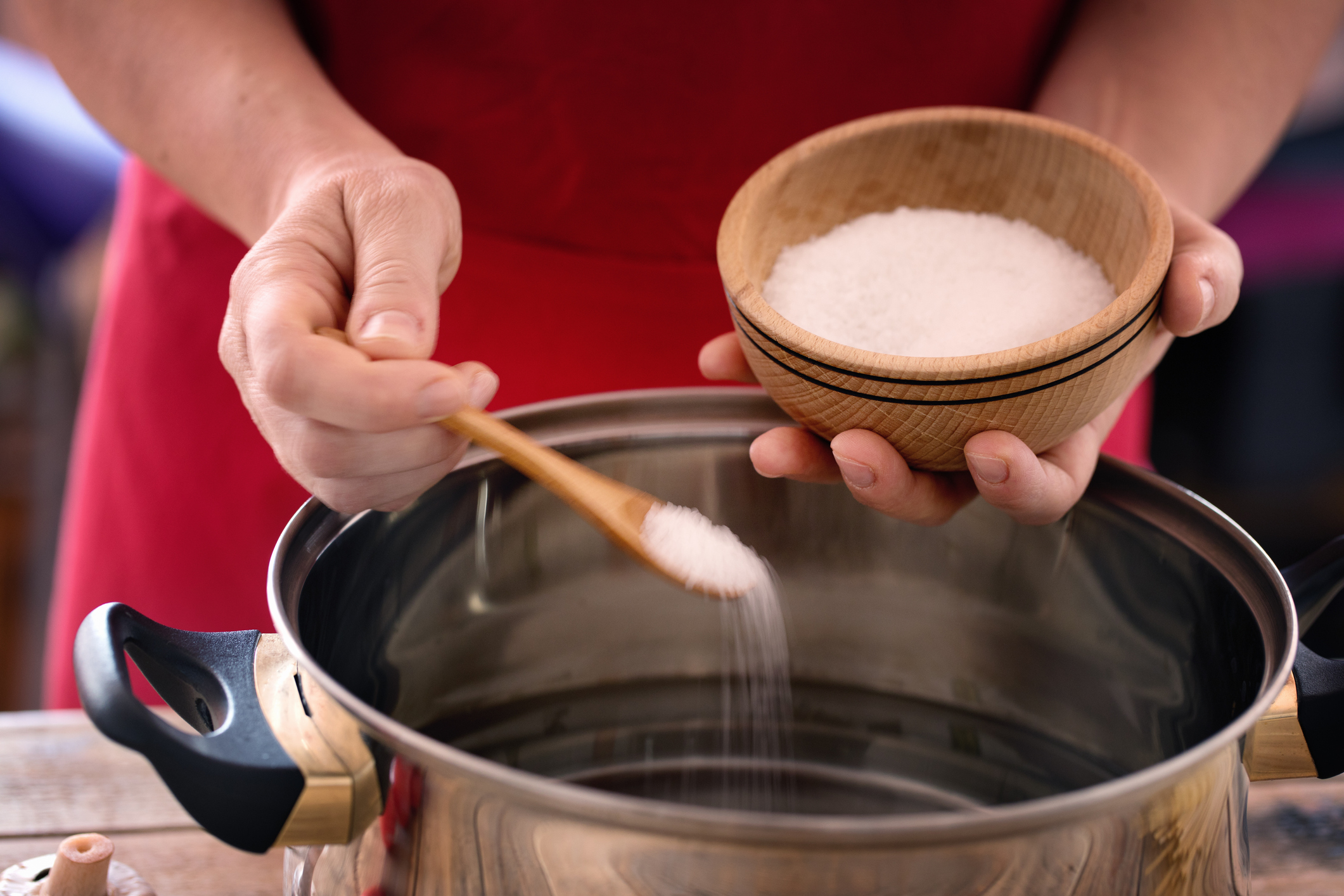 Pasta cooking - chef puts sea salt into boiling pot, close up