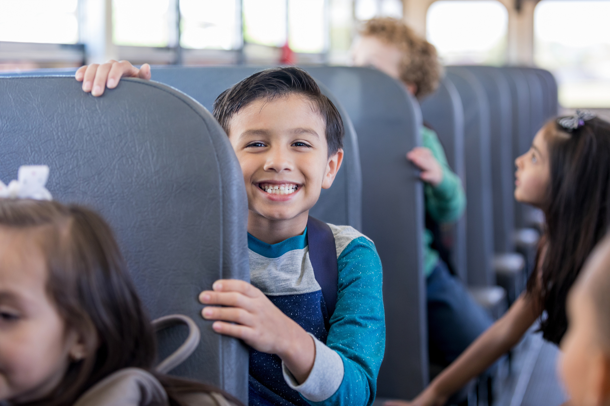 Schoolboy smiles excitedly while sitting on school bus