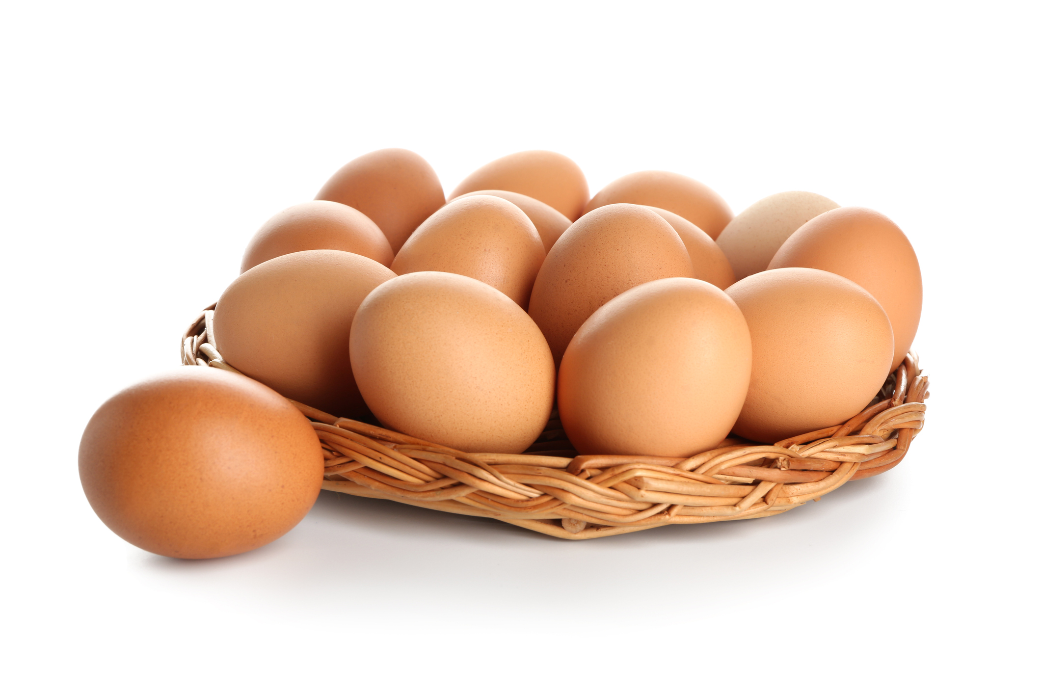 Wicker tray with raw brown chicken eggs on white background