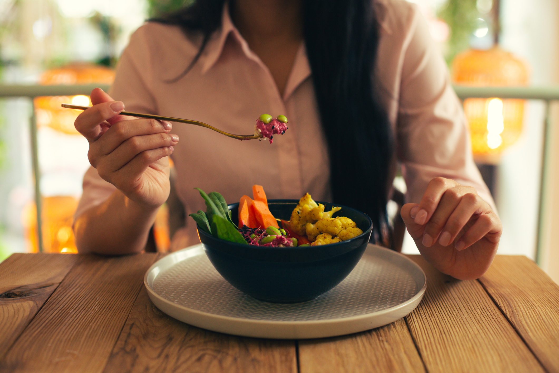 Small amount of salad on the fork in hand of woman