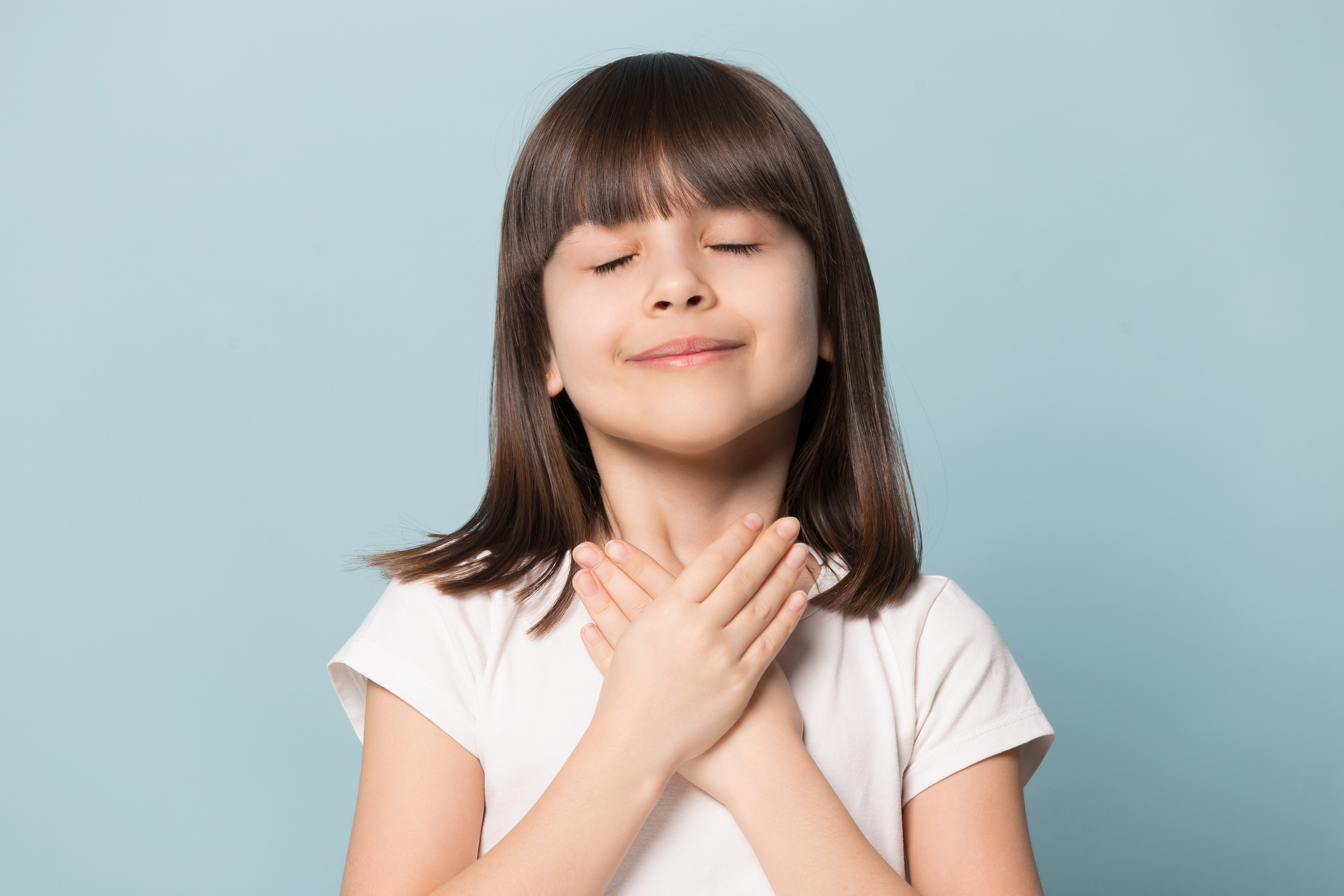 Grateful little girl closed eyes hold hand on chest