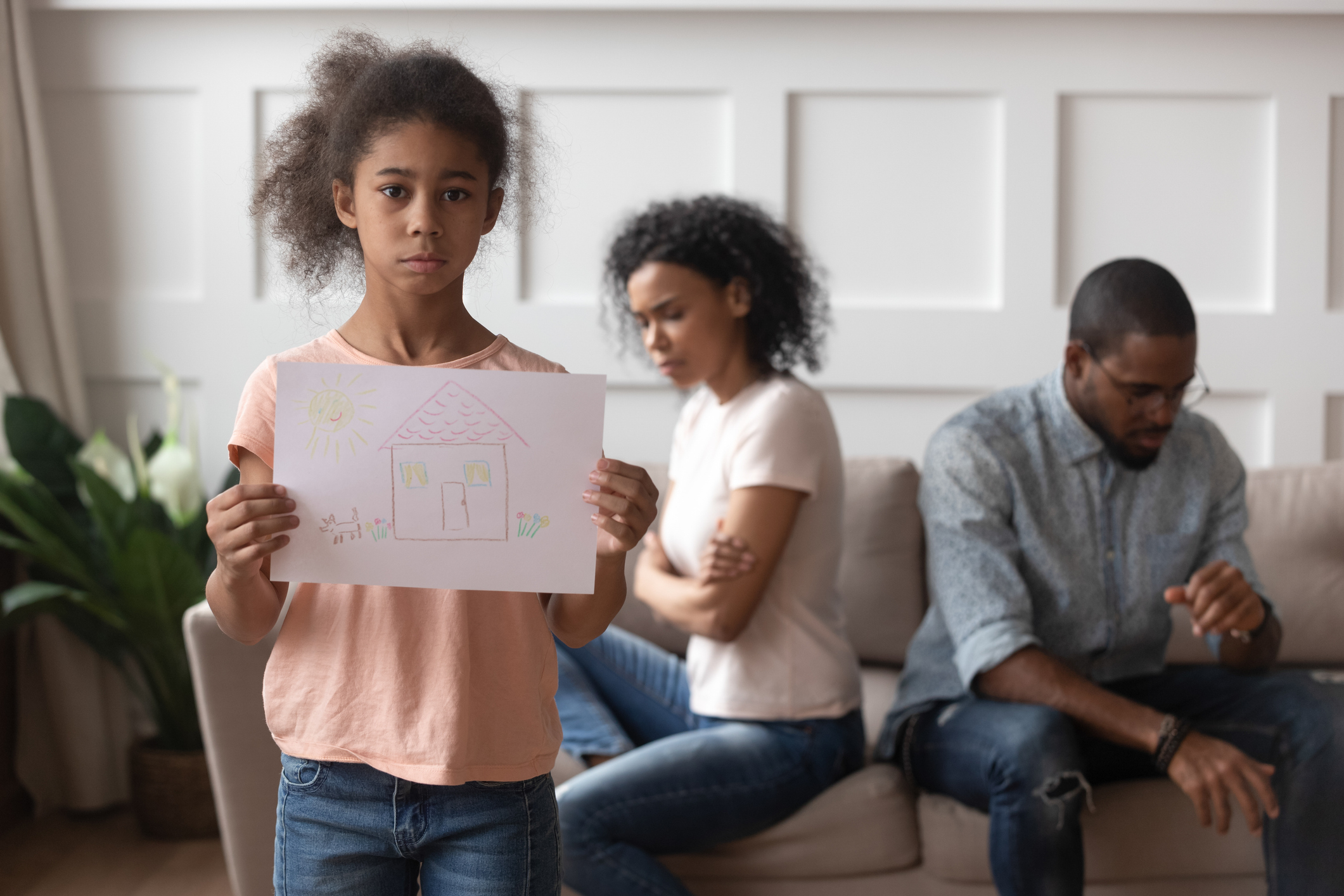 Upset worried african kid girl holding family picture, portrait