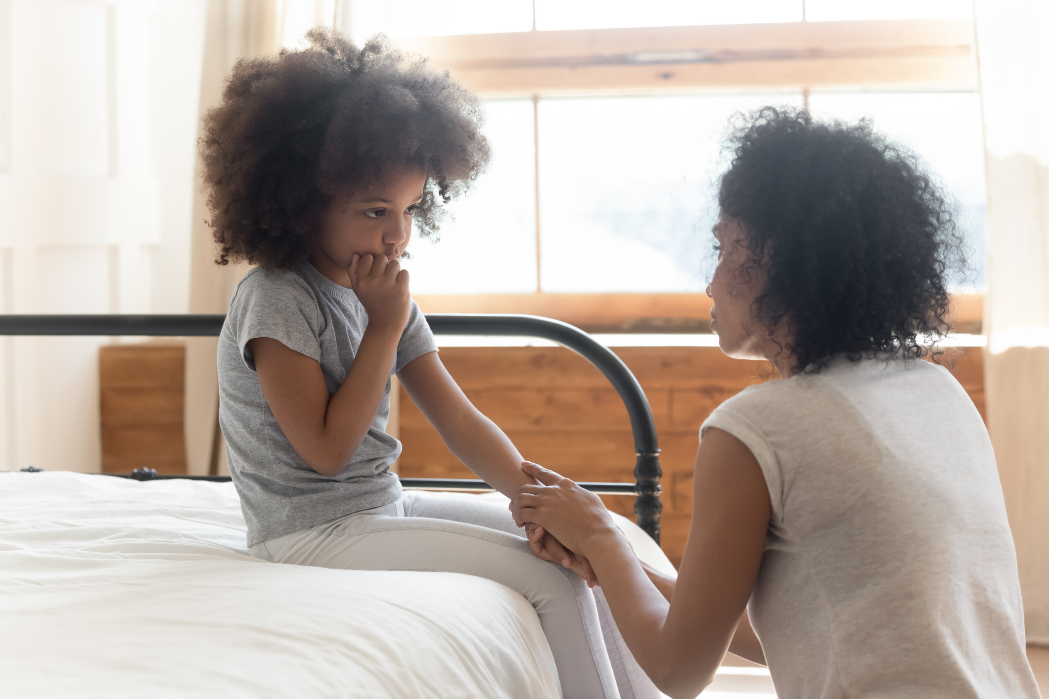 Worried african mother holding hand comforting sad little daughter