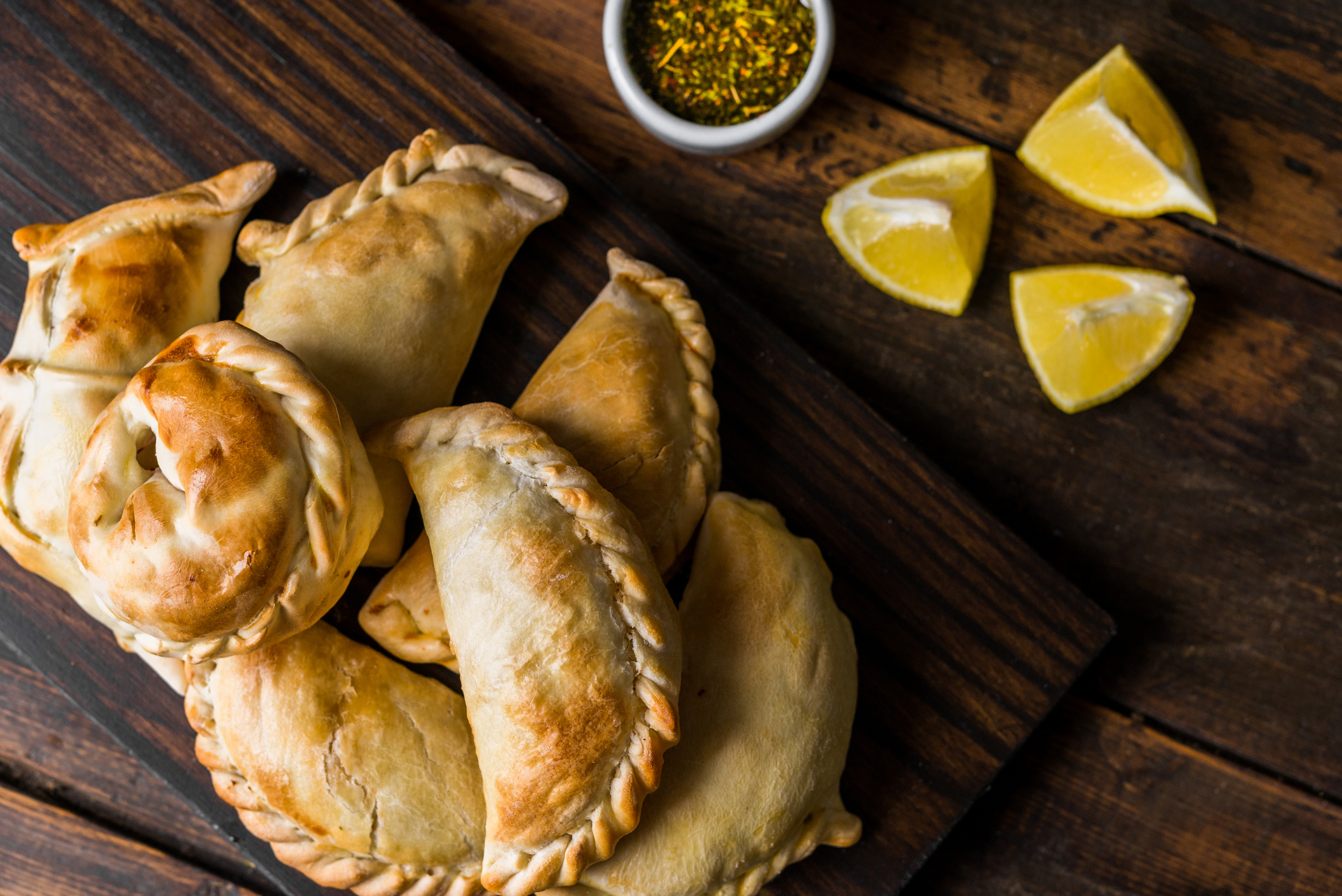 Traditional baked Argentine empanadas savoury pastries with meat beef stuffing against wooden background