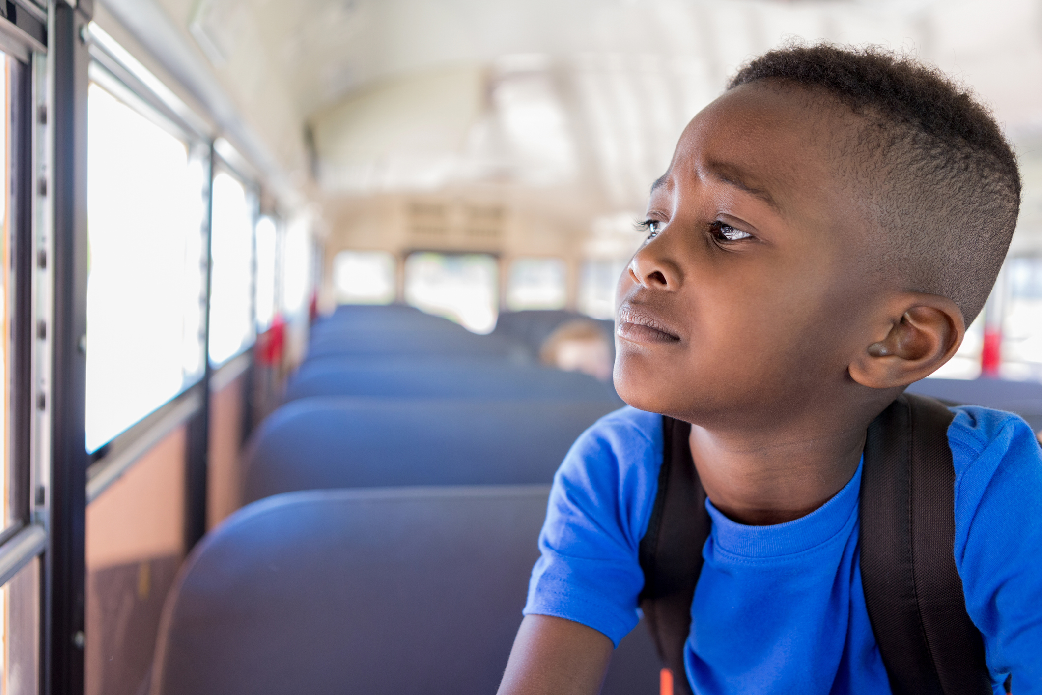 Young boy worriedly looks out bus window