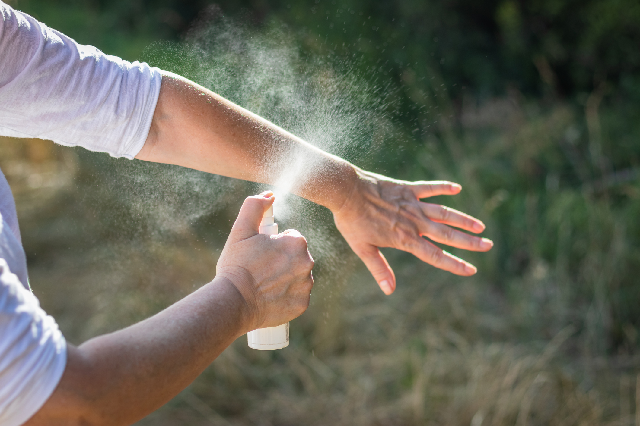 Insect repellent. Woman spraying mosquito repellent on hand.