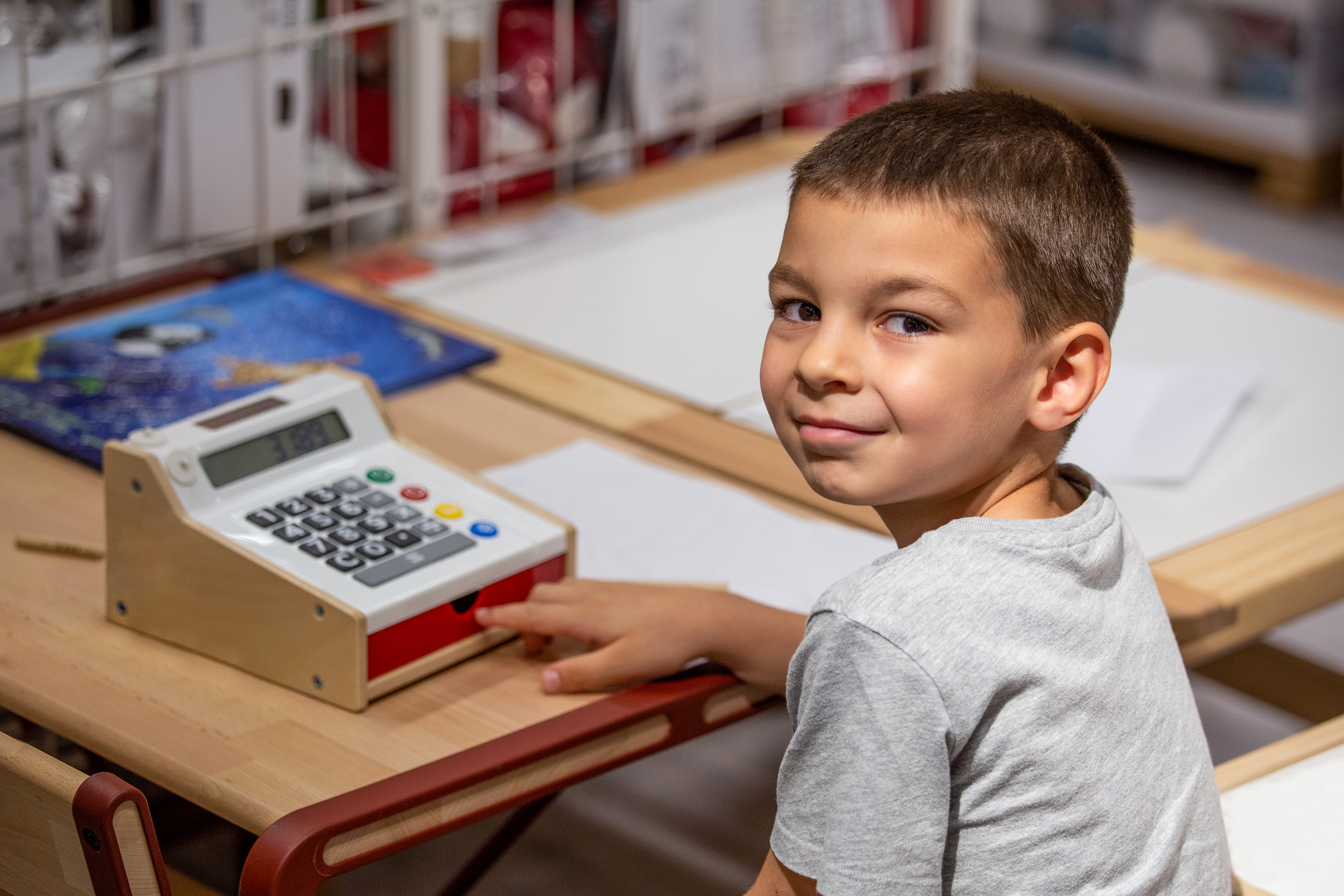 The boy plays with the children's cash register