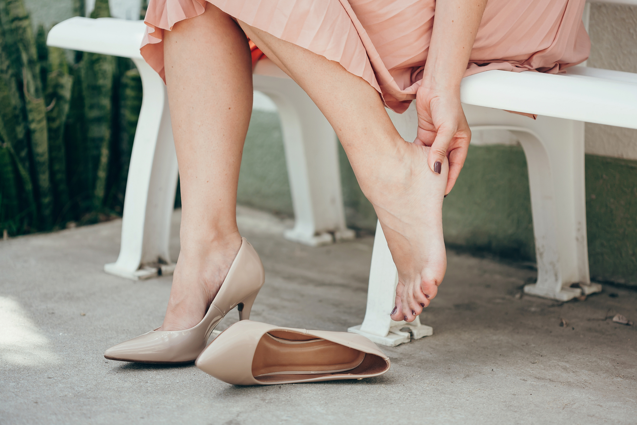 Woman suffering from leg pain outdoors because of uncomfortable shoes.