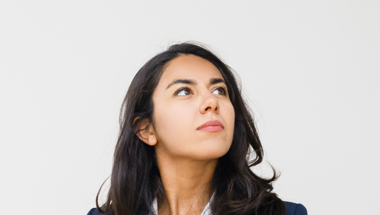 Confident businesswoman with hands in pockets looking up