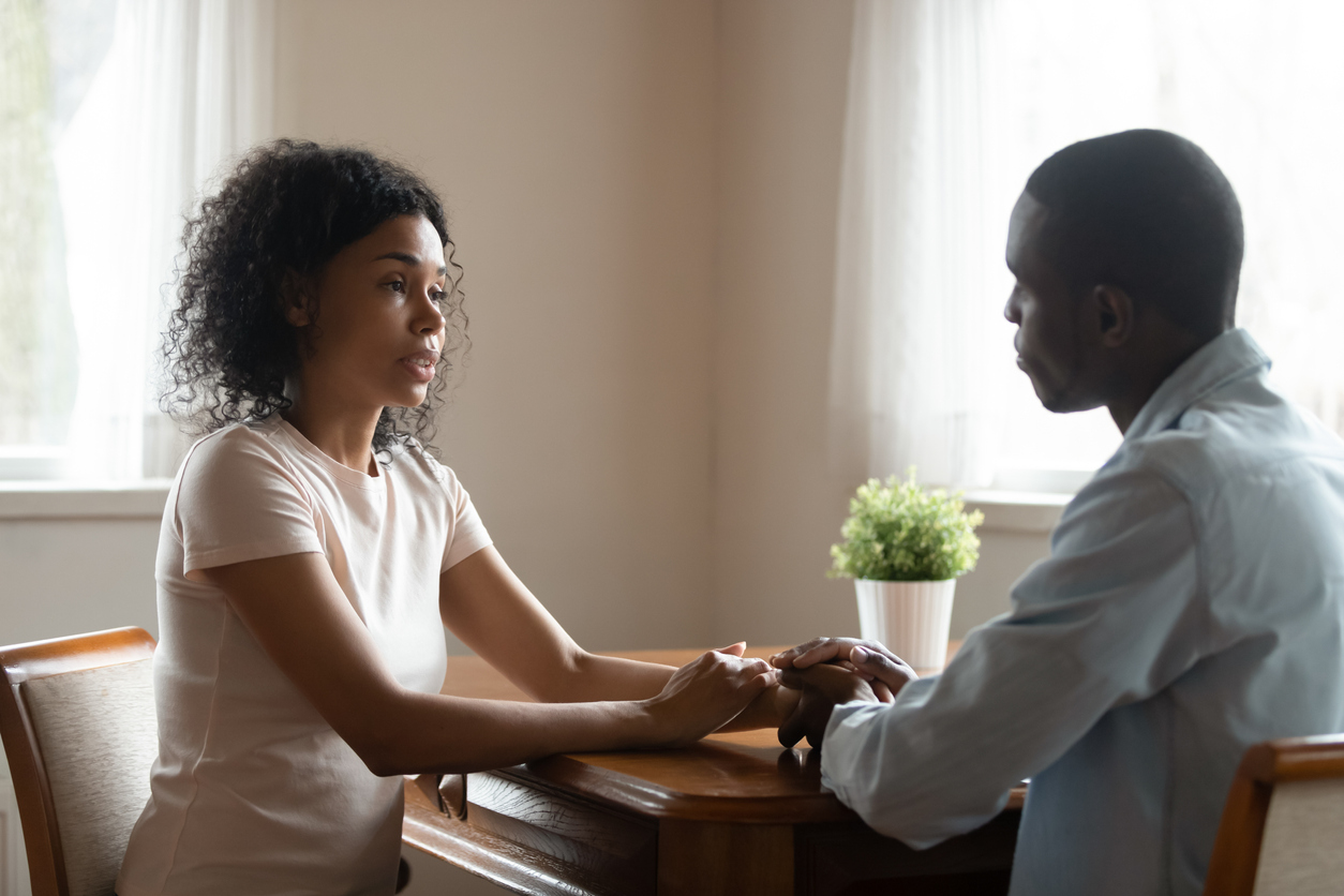 African couple sitting at table having heart-to-heart talk