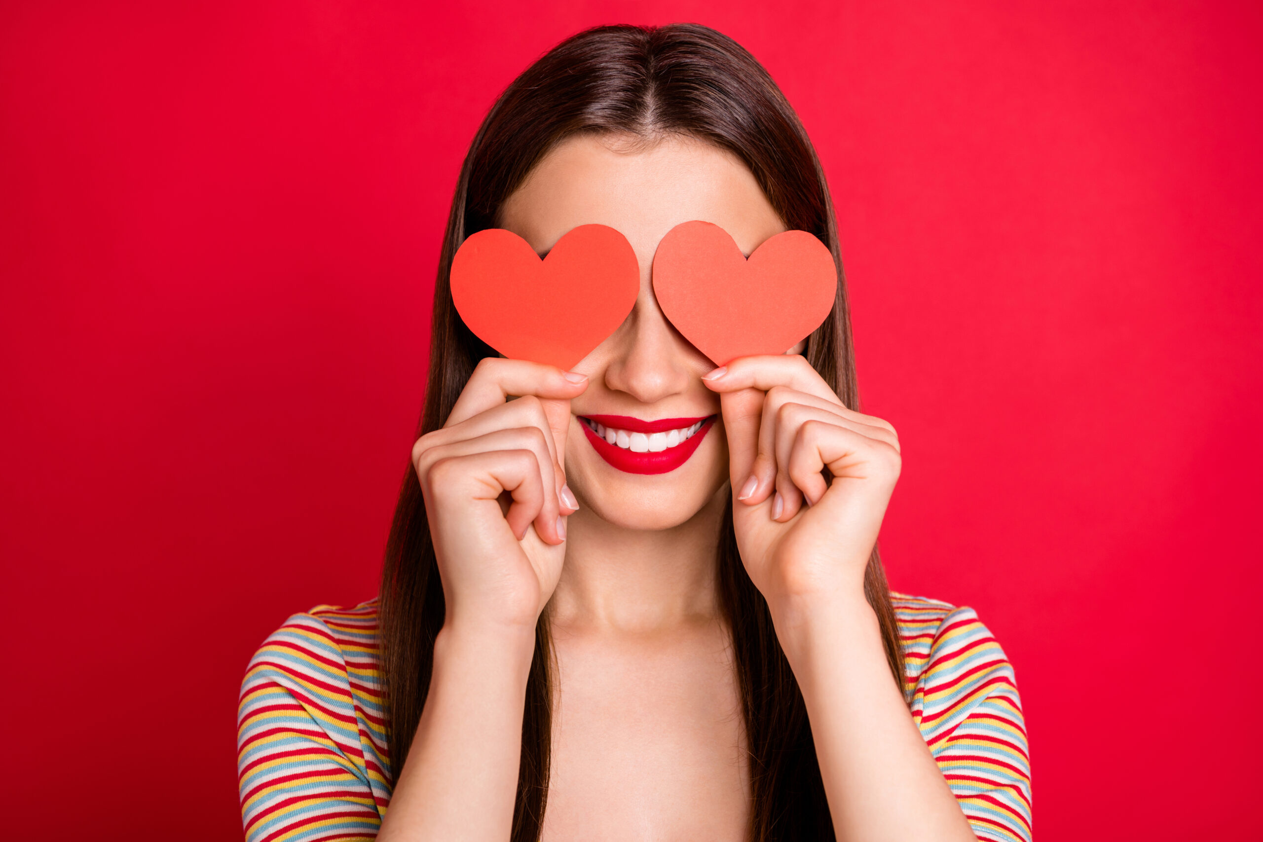 Close-up studio photo portrait of pretty charming lady with toothy beaming smile holding two small paper cards in hands isolated bright background