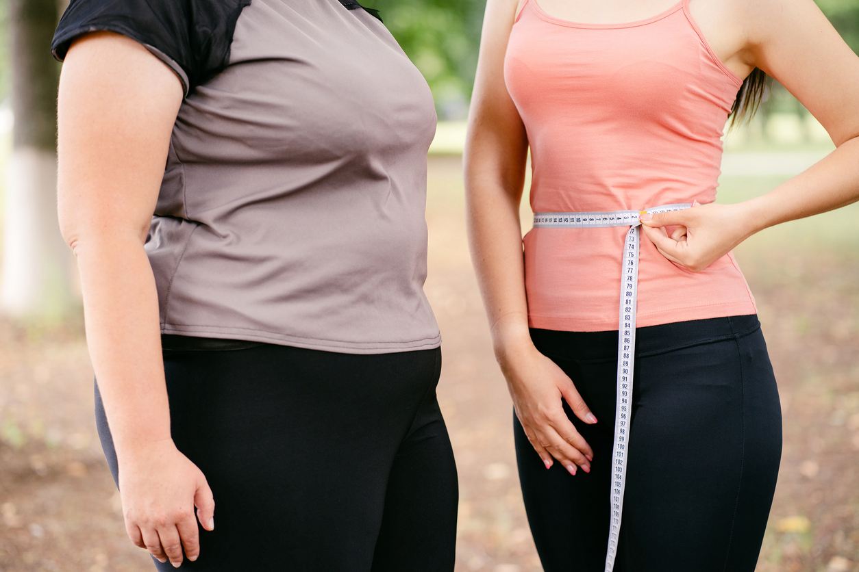 Fat and slim woman measuring waistline with tape