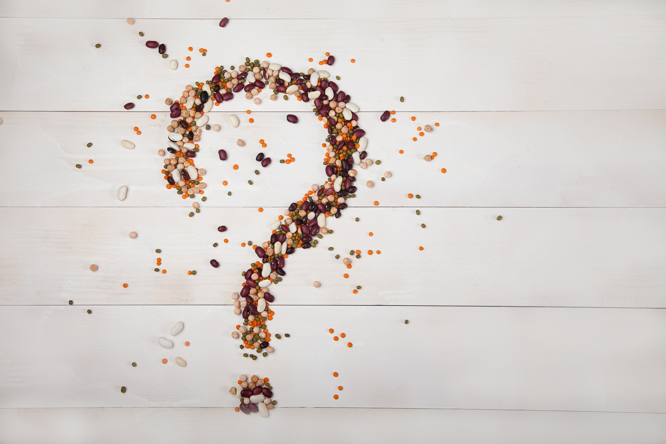 Beans, lentils, peas laid out on a white wooden background in the form of a question mark. Concept - Healthy Eating. horizontally.