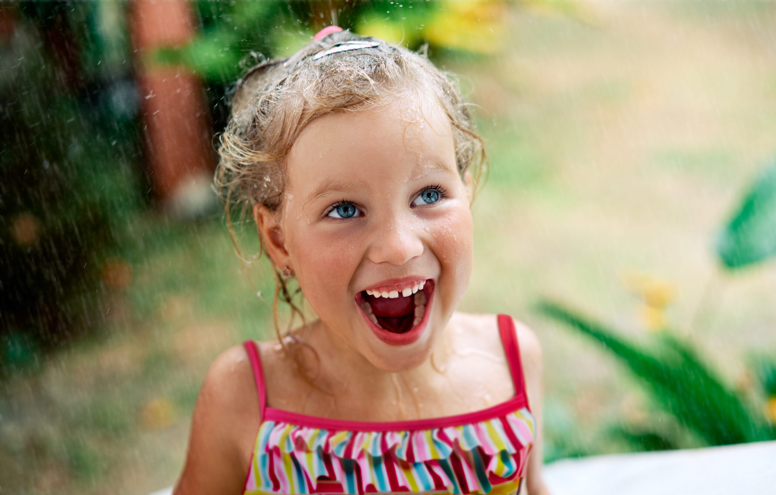 Close up portrait of happy cute little girl enjoy summer rain