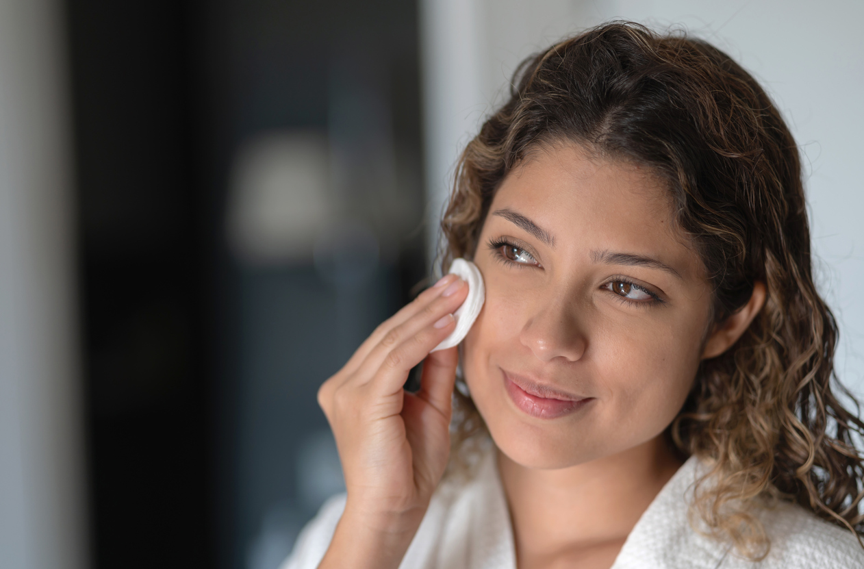 Beautiful woman cleaning her face with a cotton pad