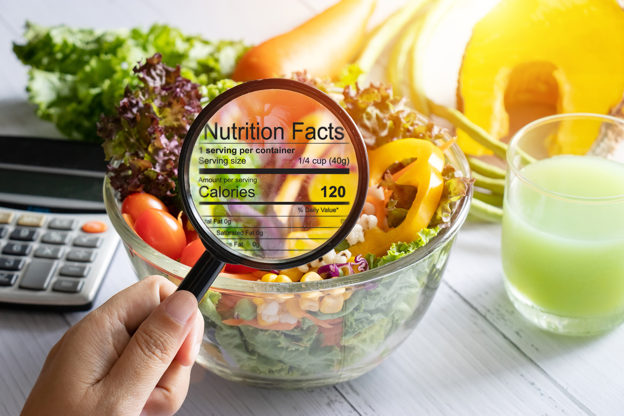 nutritional information concept. hand use the magnifying glass to zoom in to see the details of the nutrition facts from food , salad bowl