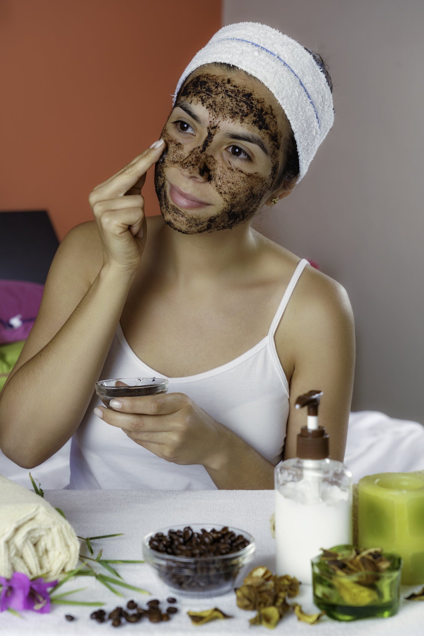 Hispanic young woman with coffee face scrub after bath looking at camera. Skin Exfoliation.