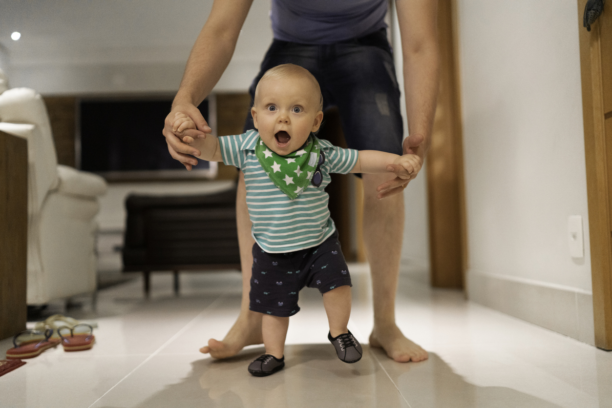 Father helping son learn to walk at home