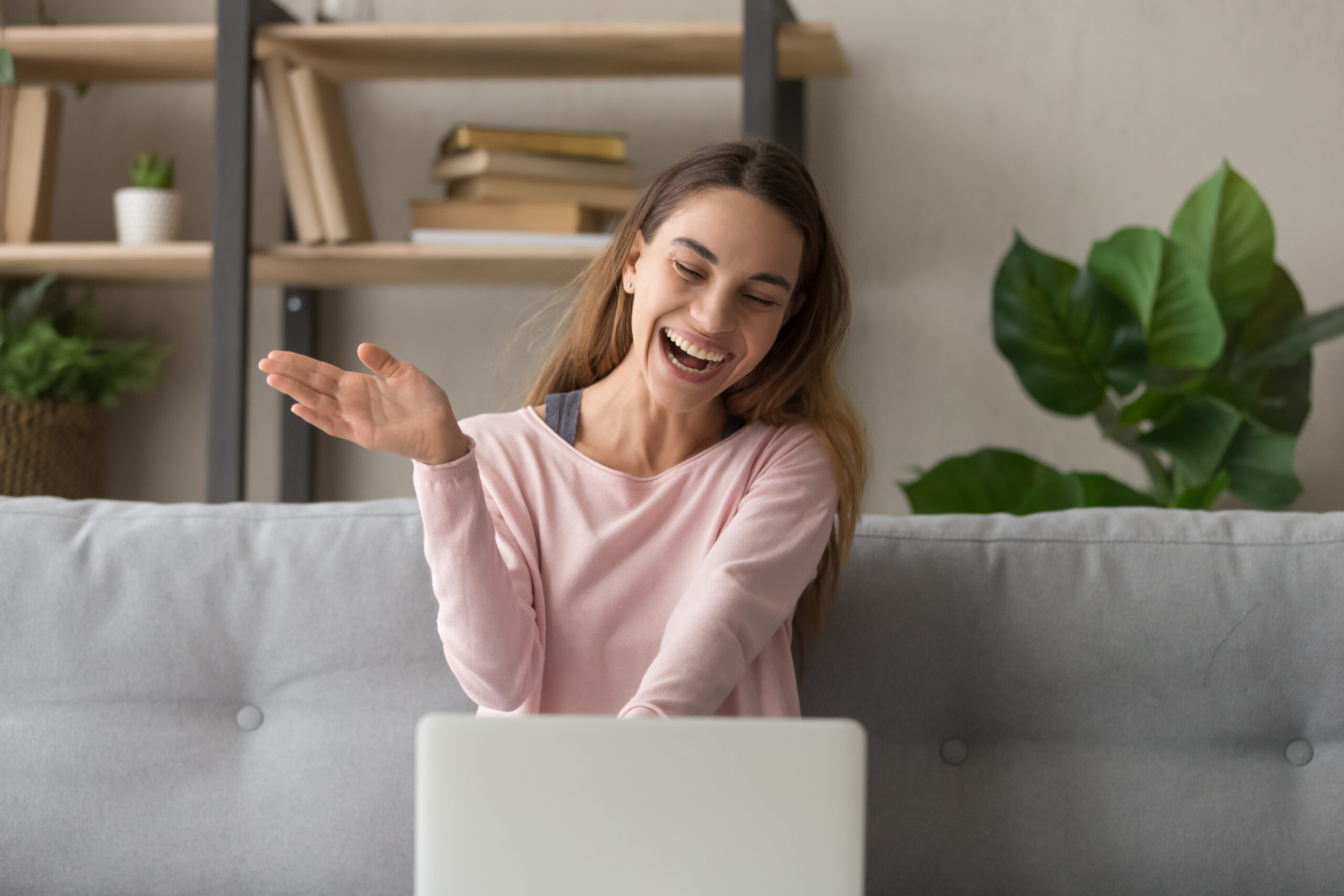 Happy girl waving having video call on laptop