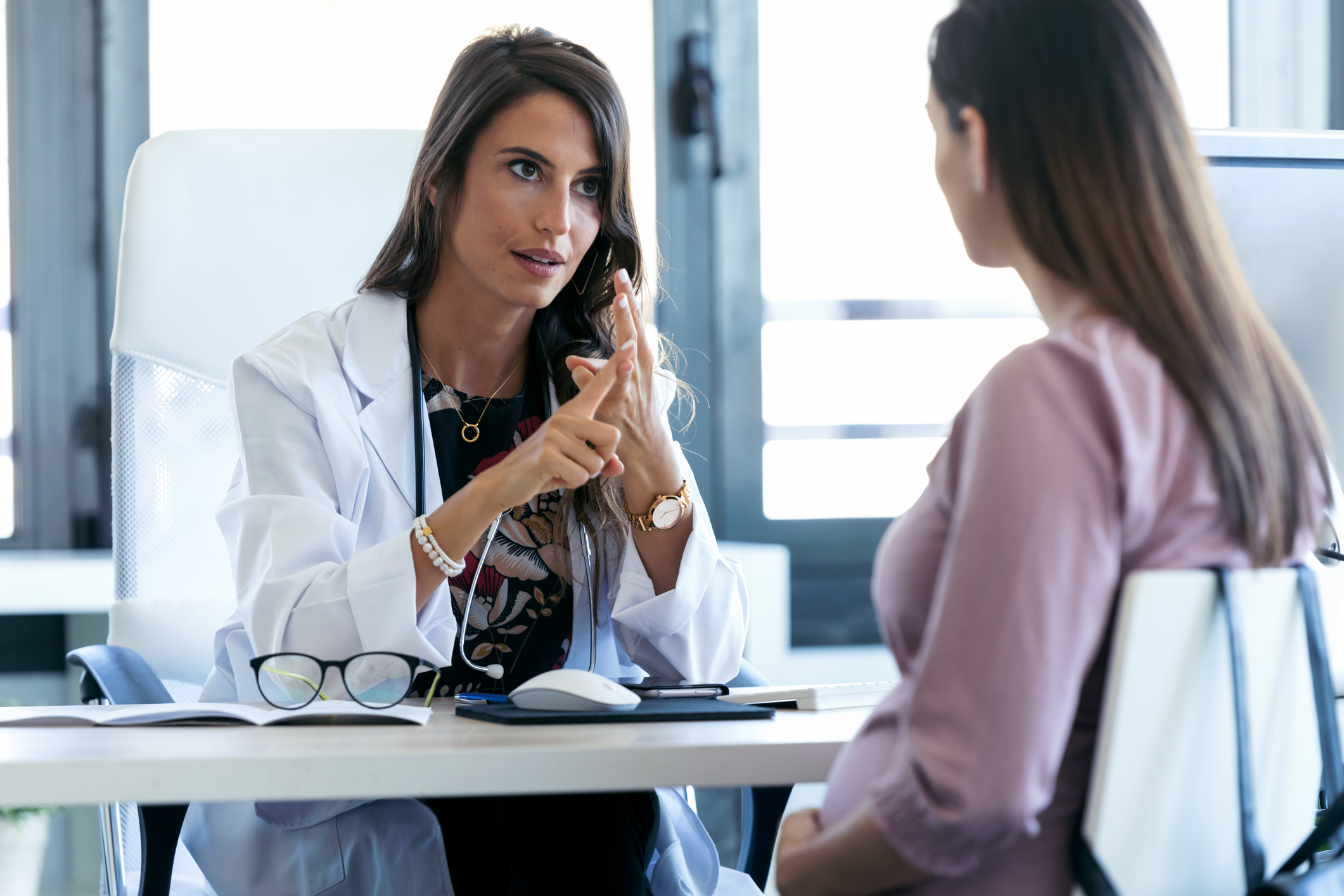 Serious young gynecologist giving guidelines to his pregnant patient in the clinic.