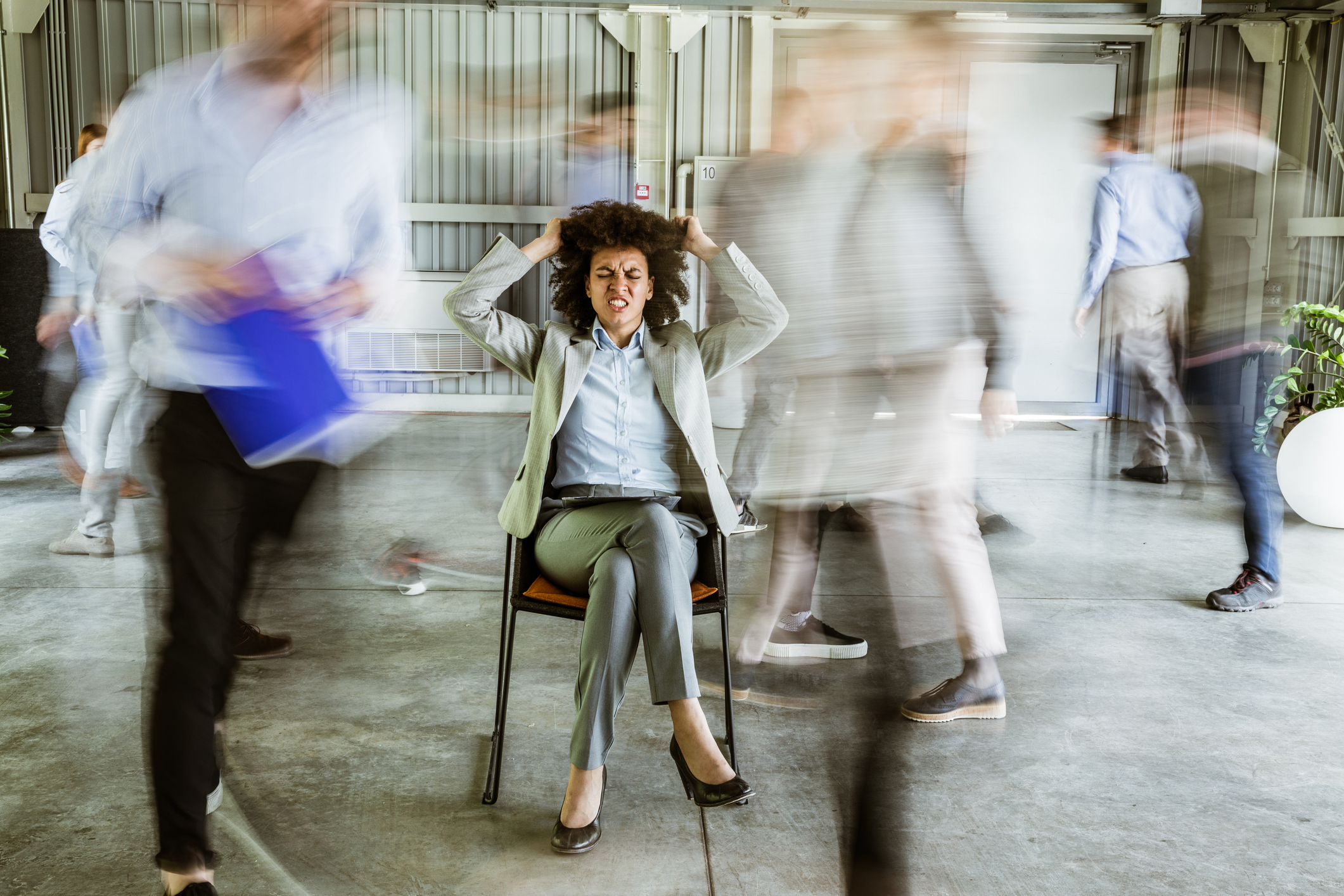 Frustrated African American businesswoman surrounded by her colleagues in blurred motion.