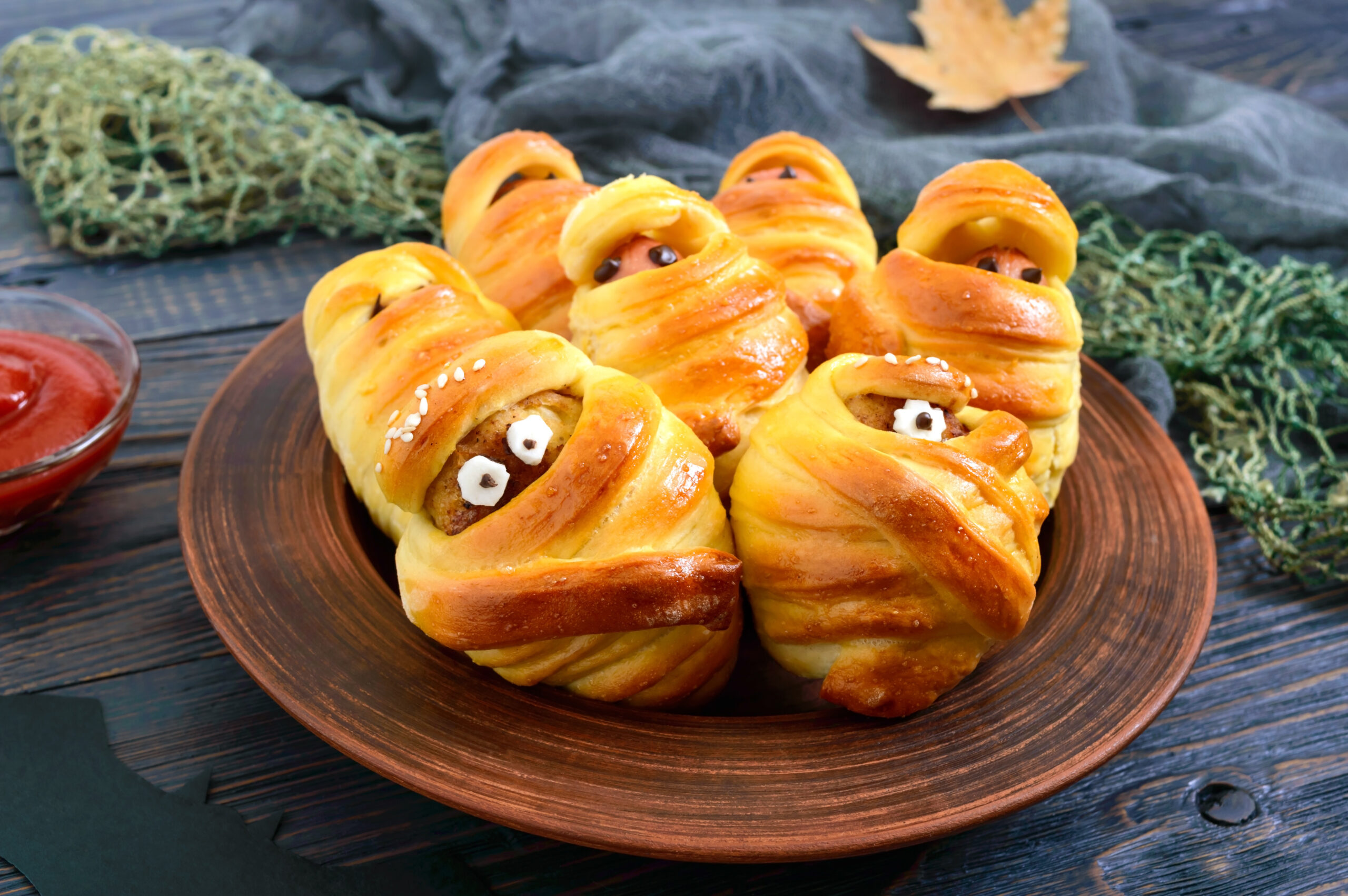 Funny sausage and cutlets mummies in dough with eyes, ketchup on table. Halloween food.