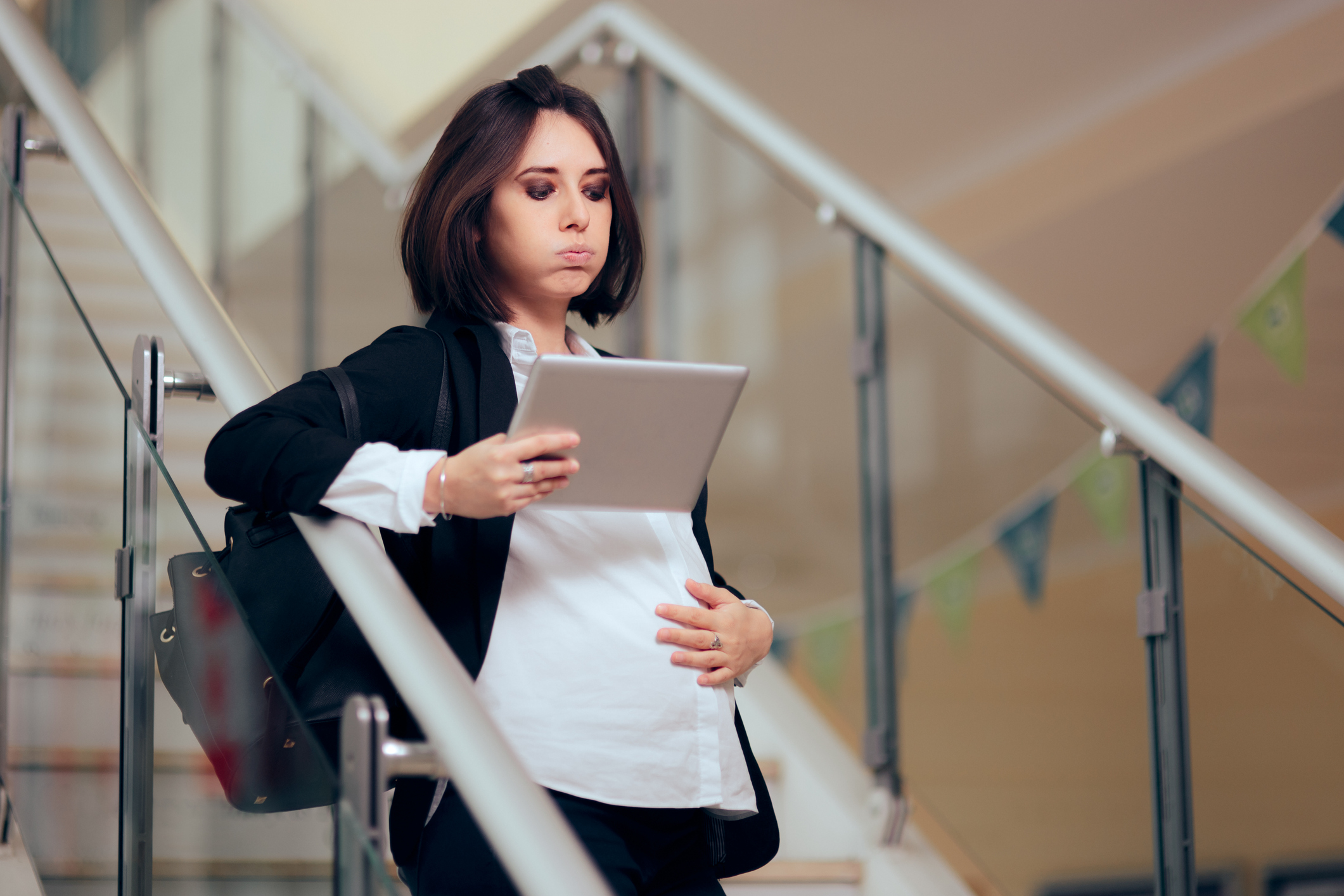 Pregnant Businesswoman with PC Tablet Felling Baby Kicking